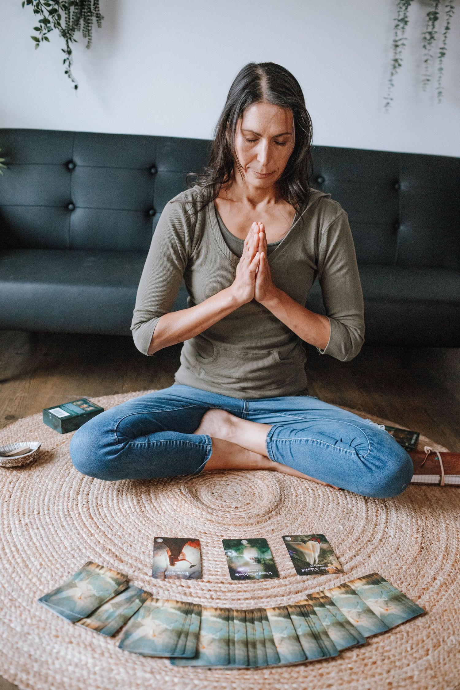 Person meditating on a round rug with tarot cards laid out in front of them.