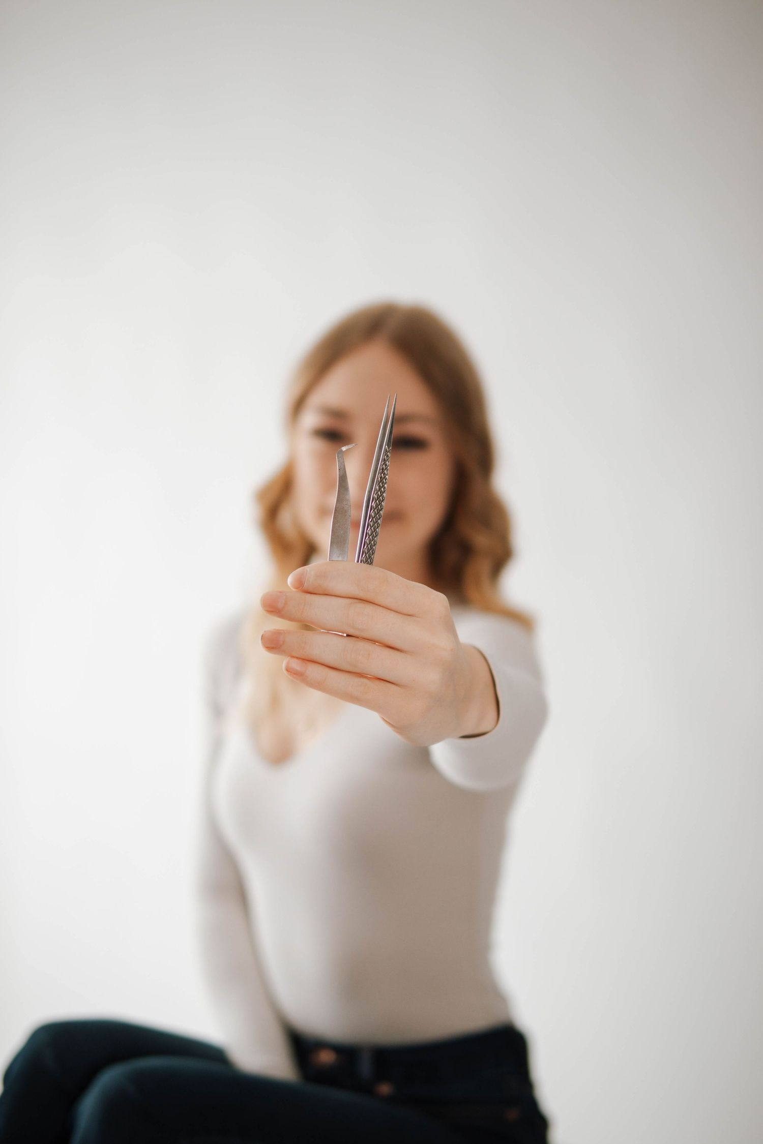 A person holding up a crystal wand against a light background in a dreamy portrait style.
