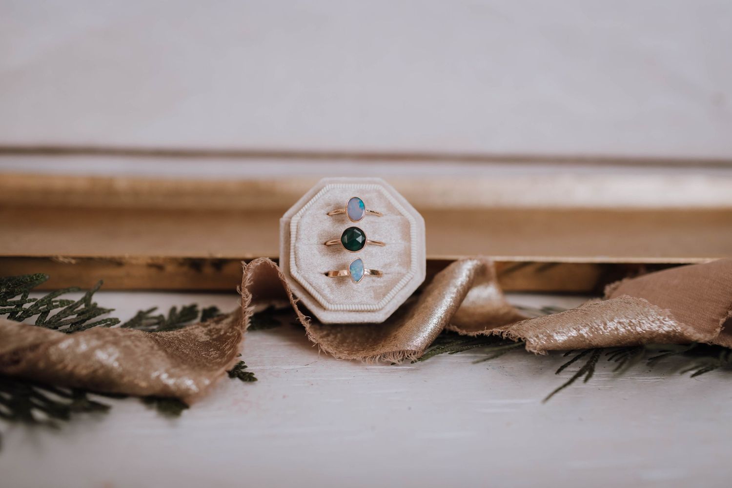 Vintage-style octagonal ring box with delicate details surrounded by pine sprigs.
