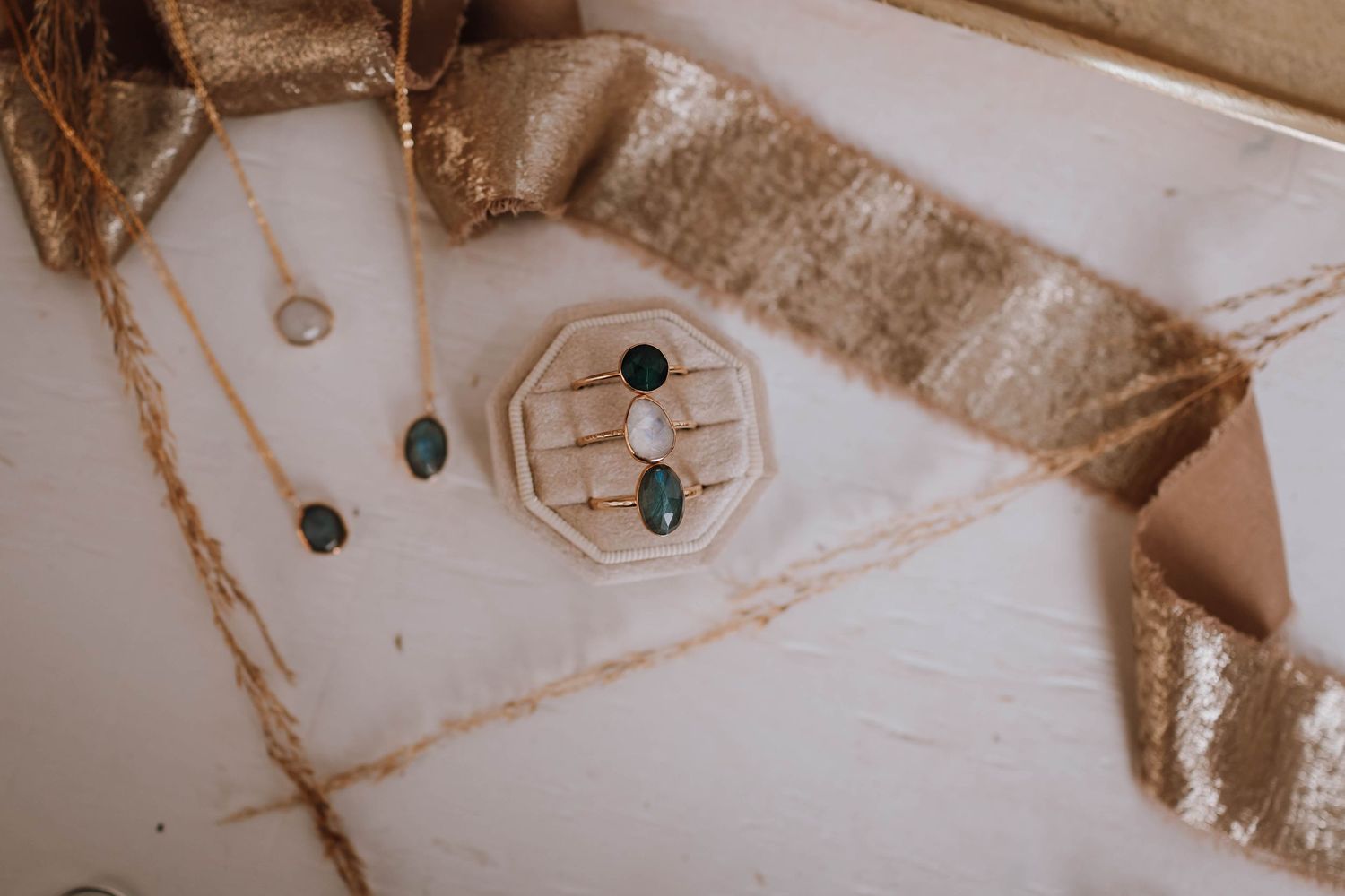 Artistic flat lay of jewelry box containing rings on white surface with fabric accents.