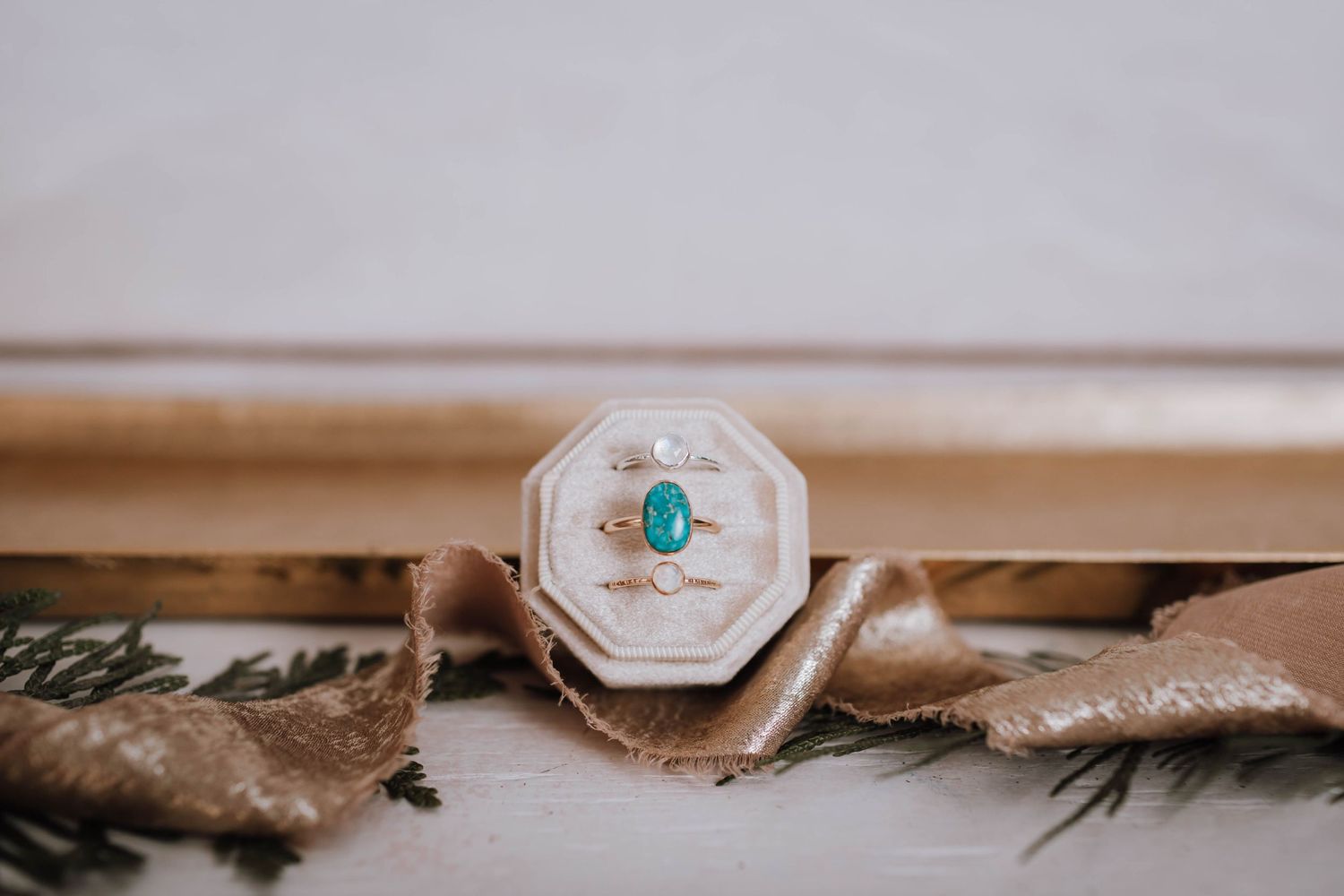 Octagonal ring box showcasing a turquoise gemstone ring on rustic surface.