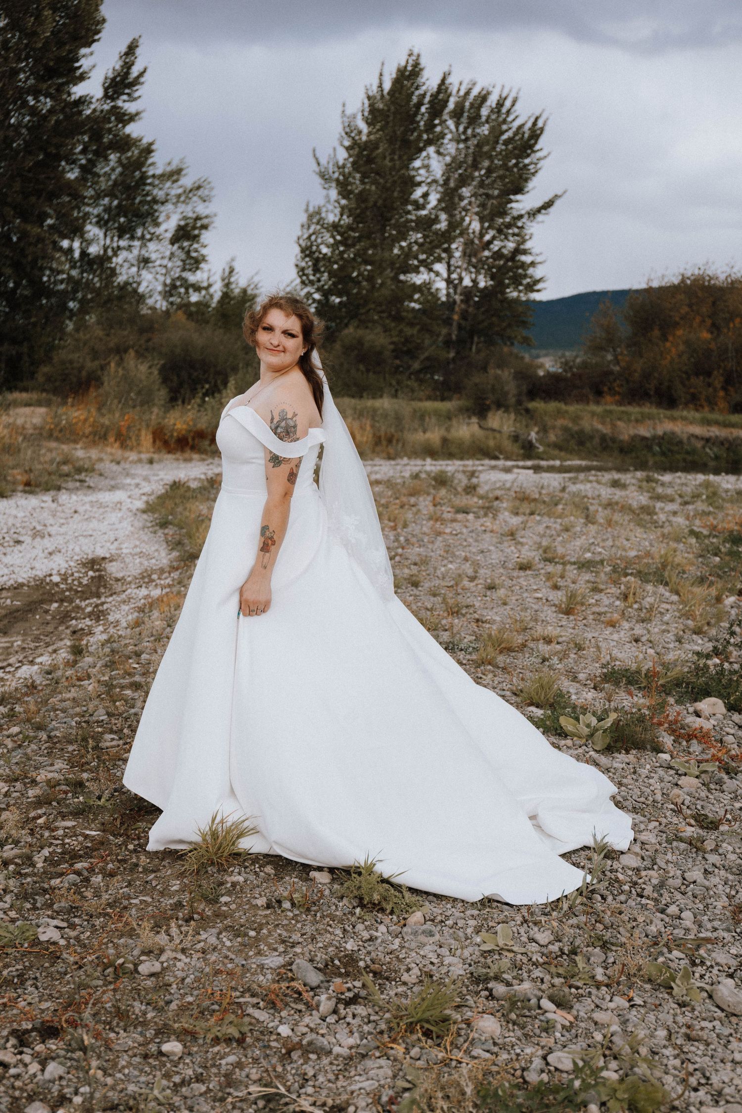A wedding dress flows elegantly across rocky terrain under moody skies in a series of artistic bridal portraits.