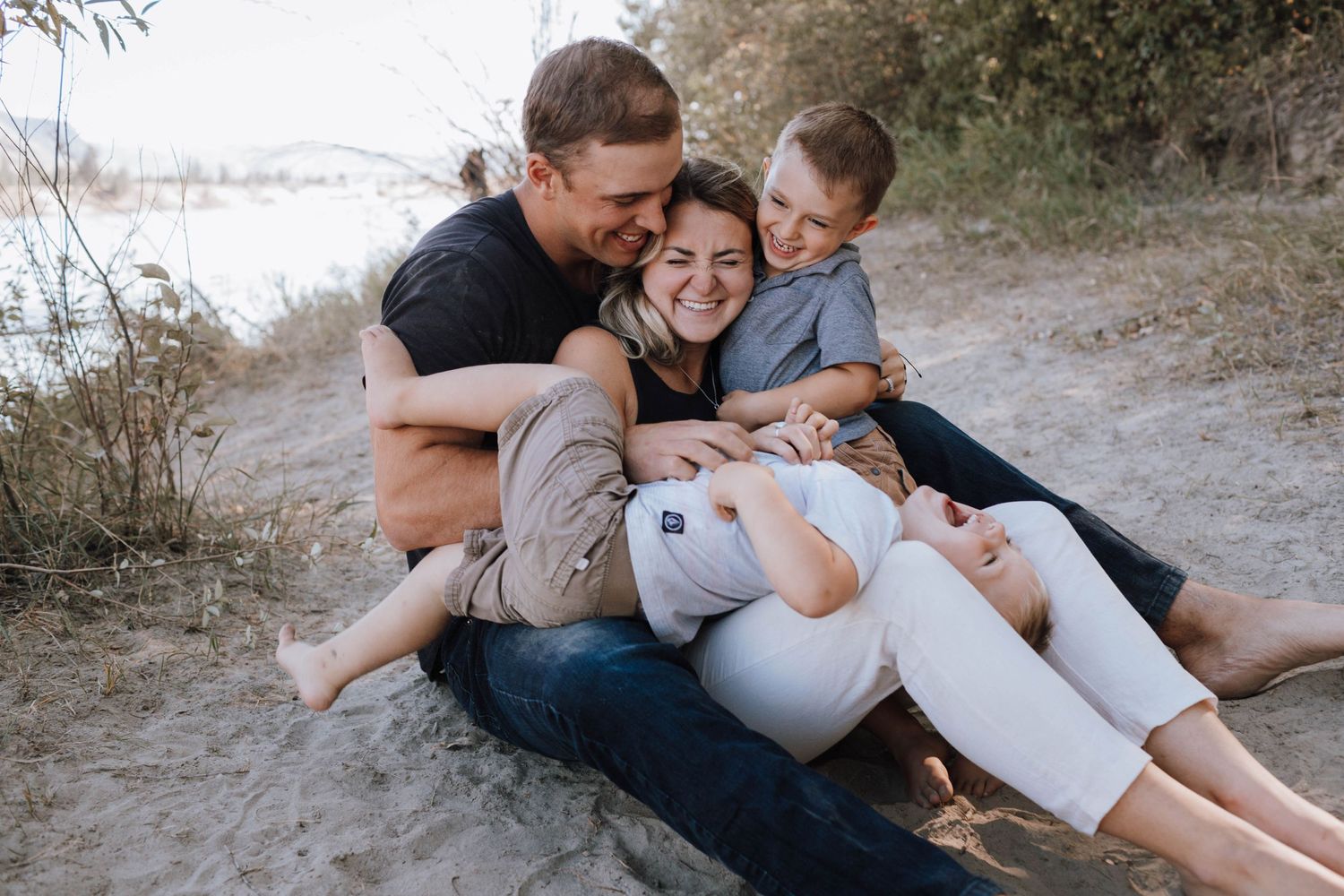 Intimate family moment captured on a sandy beach path with everyone cuddling close together.