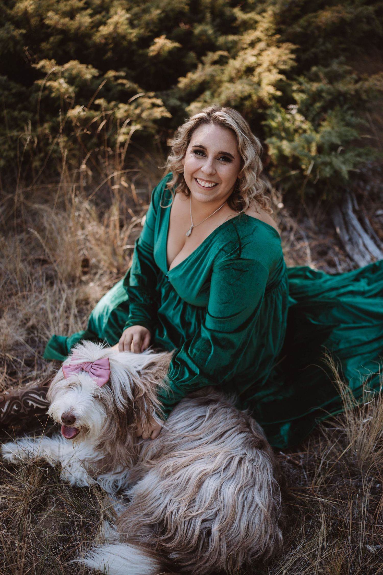 Outdoor portrait session with fluffy white dog against dry grass background.