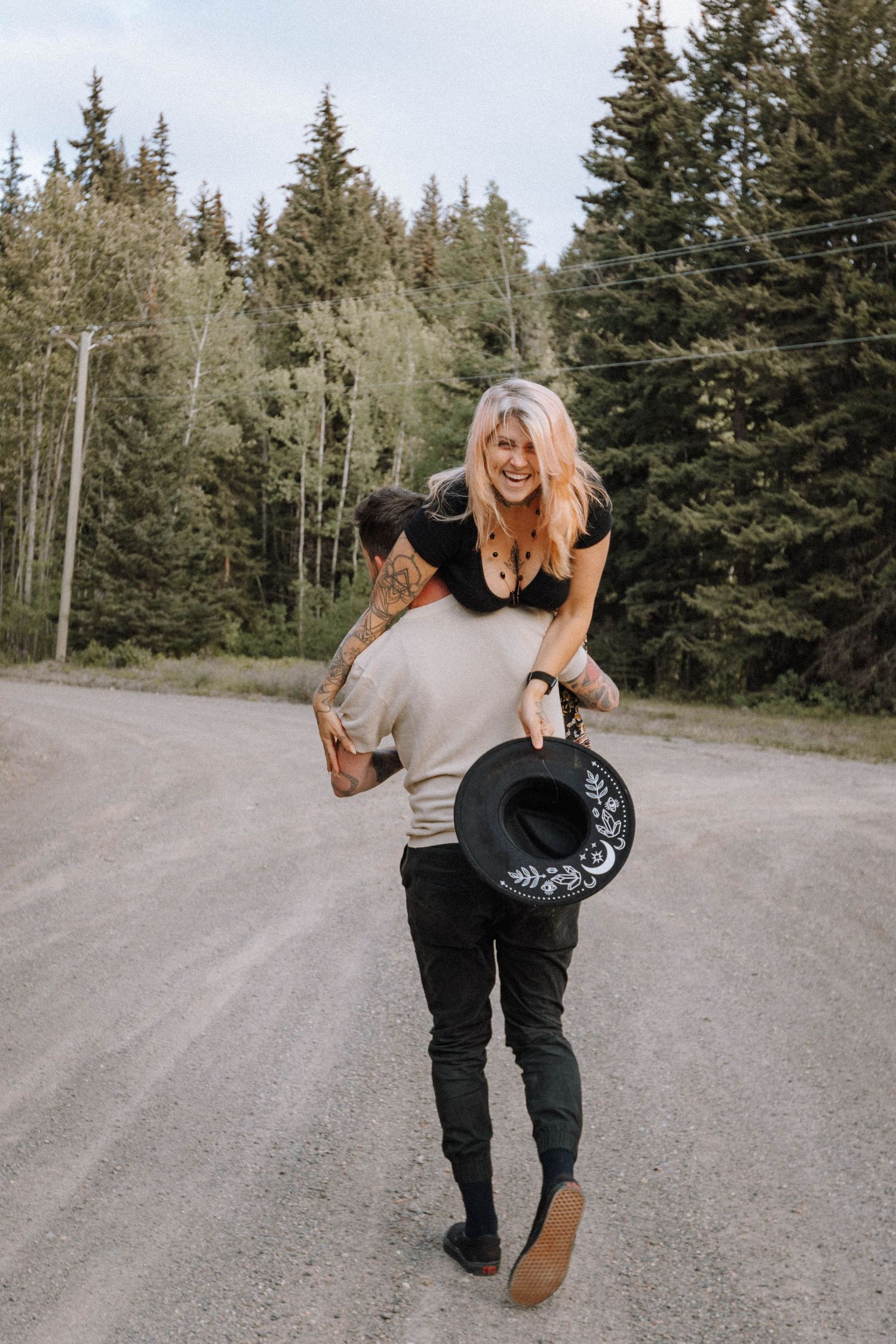 A sequence of playful dance moves performed on a gravel road surrounded by evergreen trees.