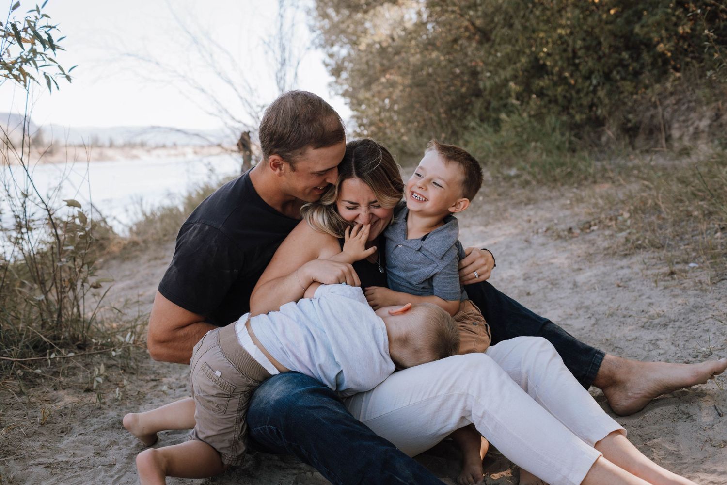 Candid family photo showing playful interaction and laughter while sitting on a sandy beach path.