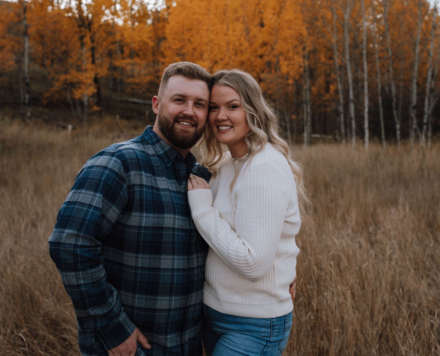 Intimate portrait of couple against backdrop of fall-colored aspen trees.