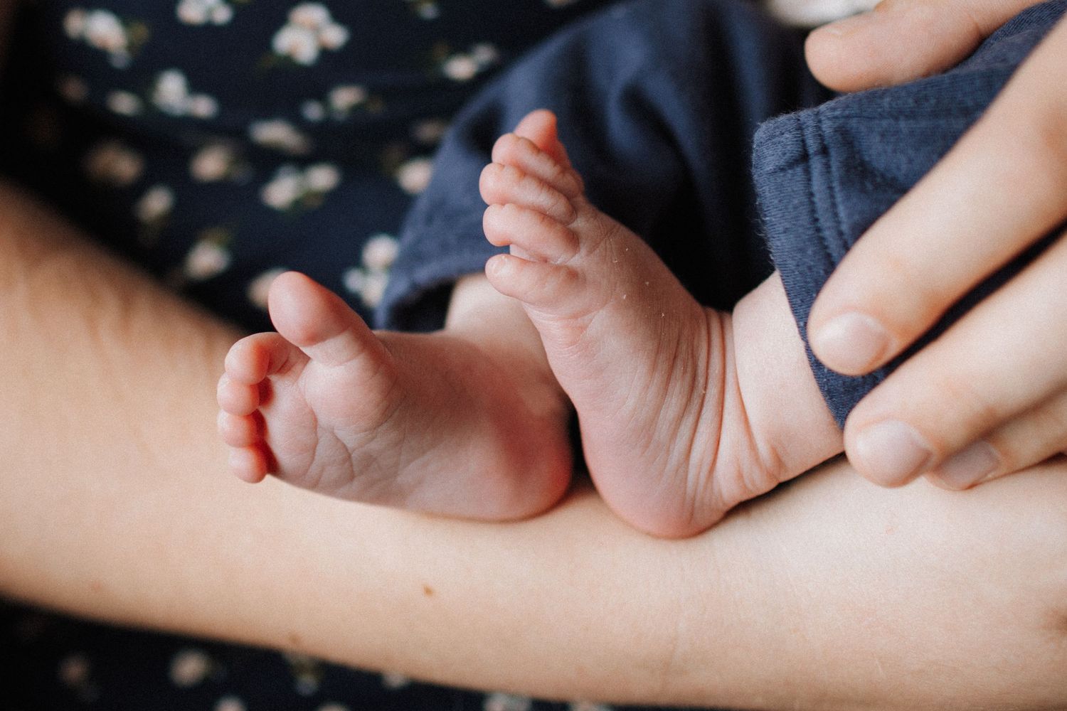 Close-up of a newborn baby's tiny feet resting in a parent's gentle hands.