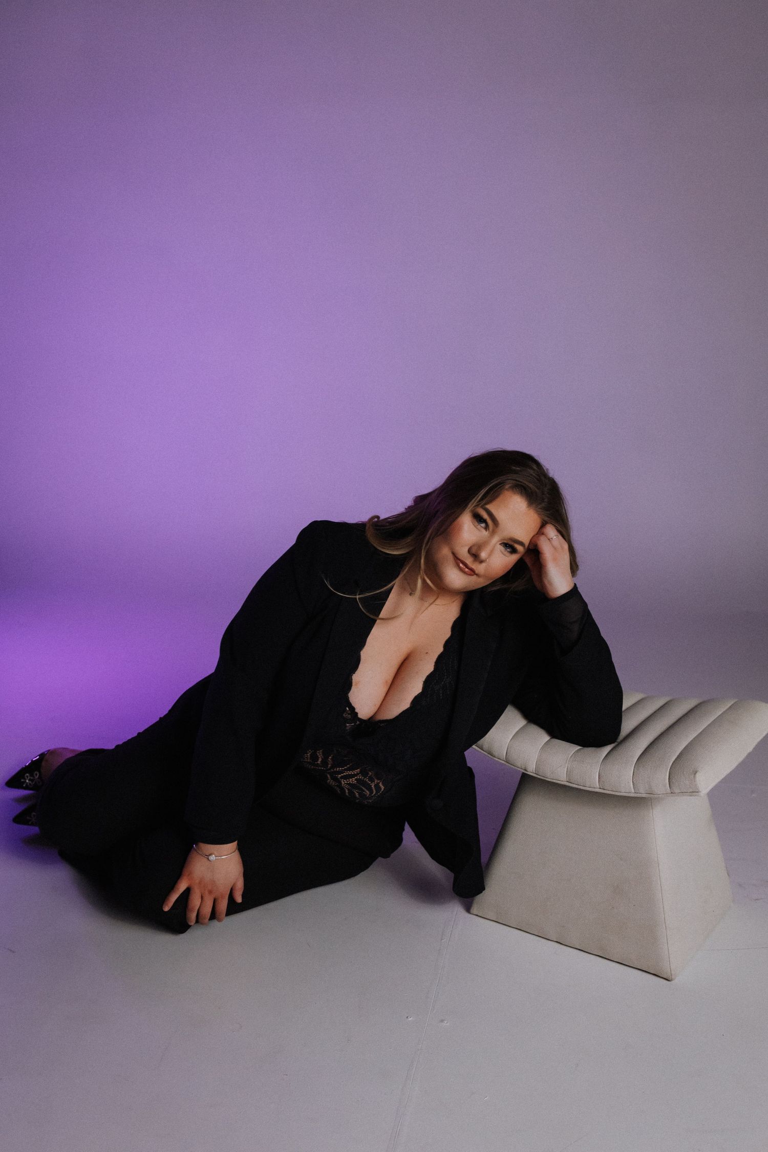 Fashion portrait with black outfit against purple backdrop with modern white furniture accent.