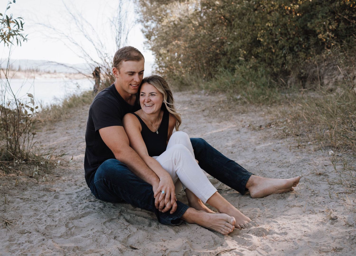 Couple relaxing together on sandy beach path with natural scenery in background.