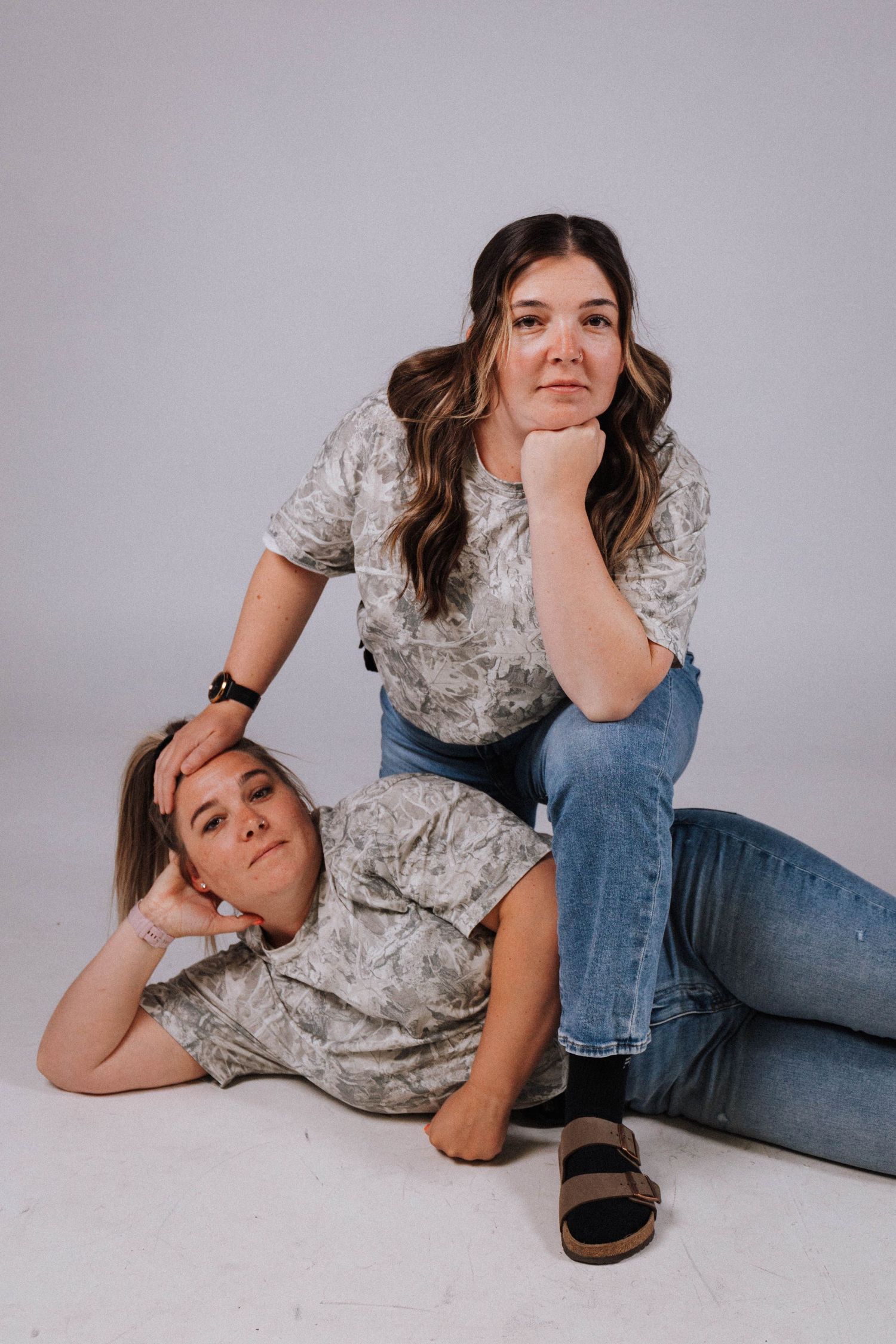A series of casual poses on a light gray background wearing blue jeans and a floral top.