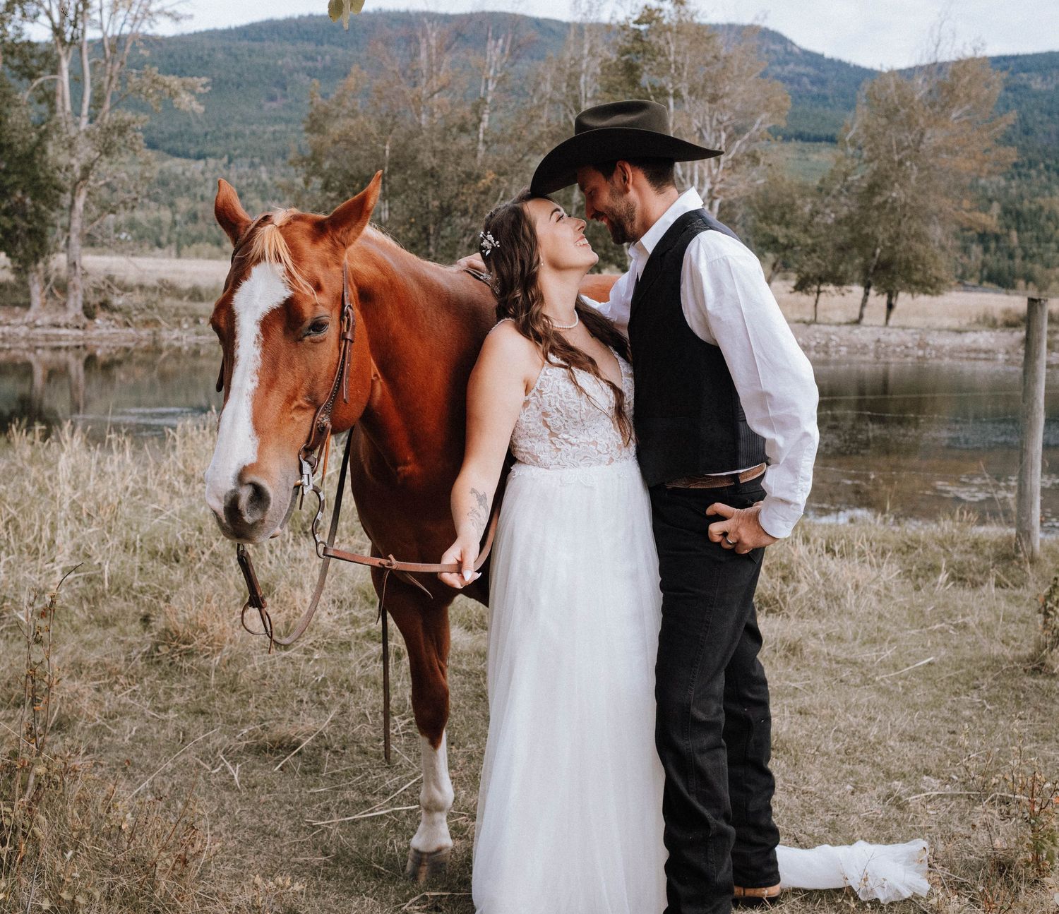Country western wedding portrait with brown horse in mountain landscape.