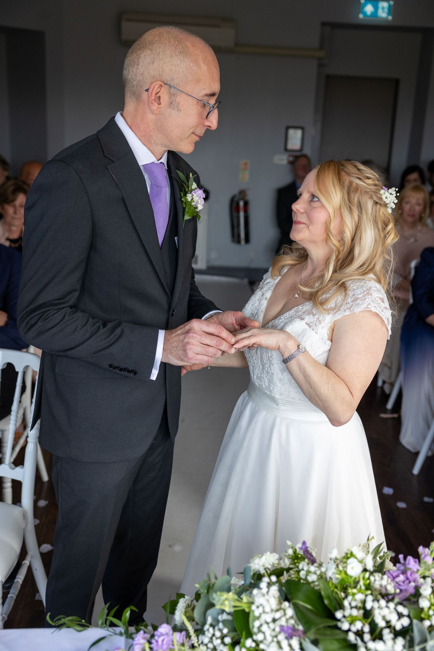 A tender moment during a wedding ceremony with floral decorations in the foreground.