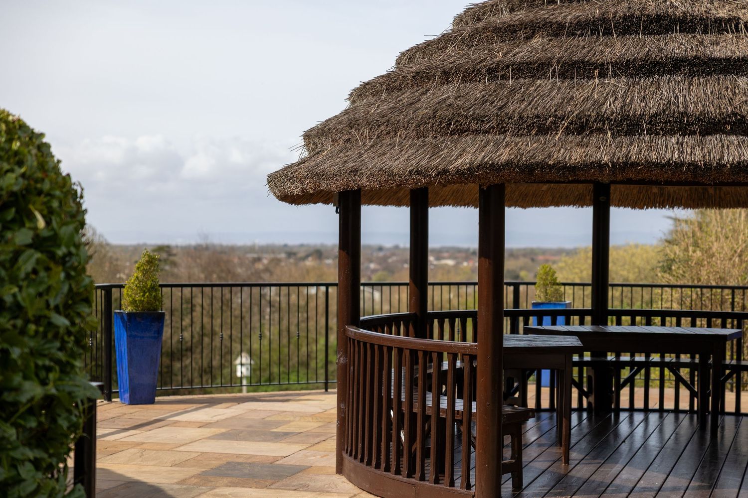 A thatched-roof gazebo overlooking a scenic landscape view.