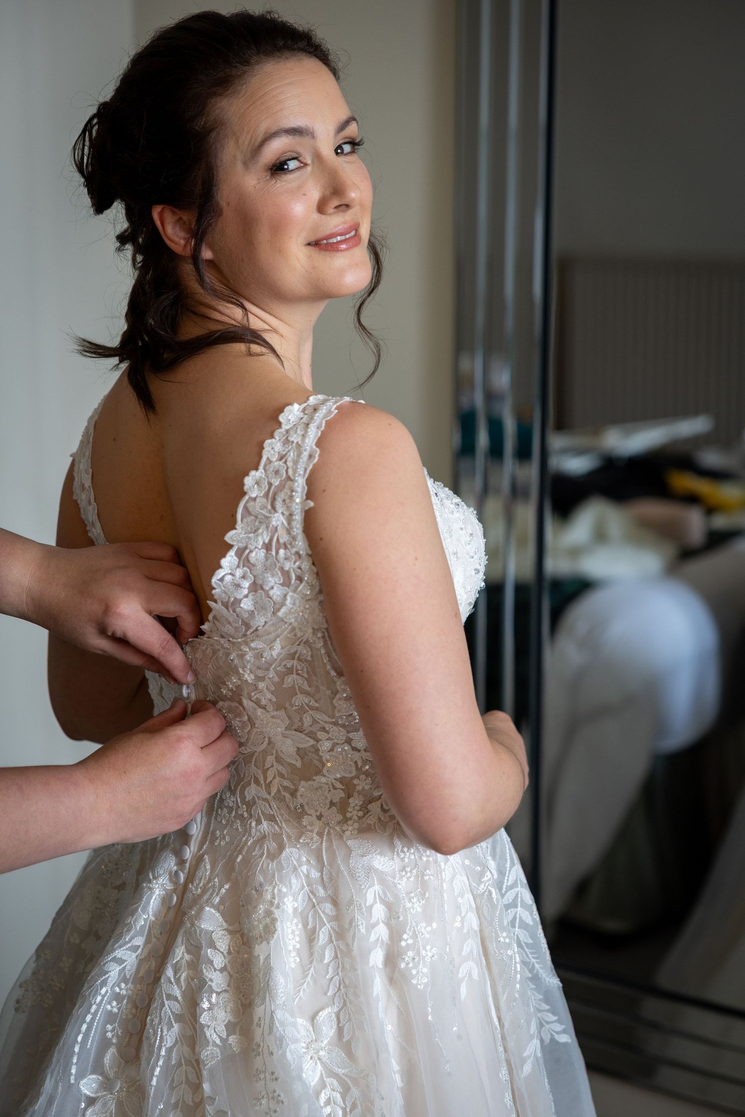 A behind-the-scenes wedding preparation shot showing intricate lace details on a bridal gown.