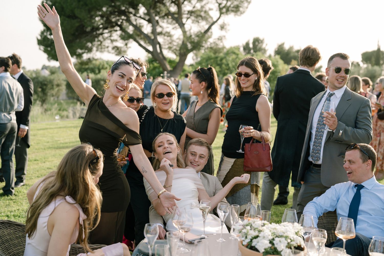 Outdoor wedding reception with guests mingling and celebrating in a garden setting.