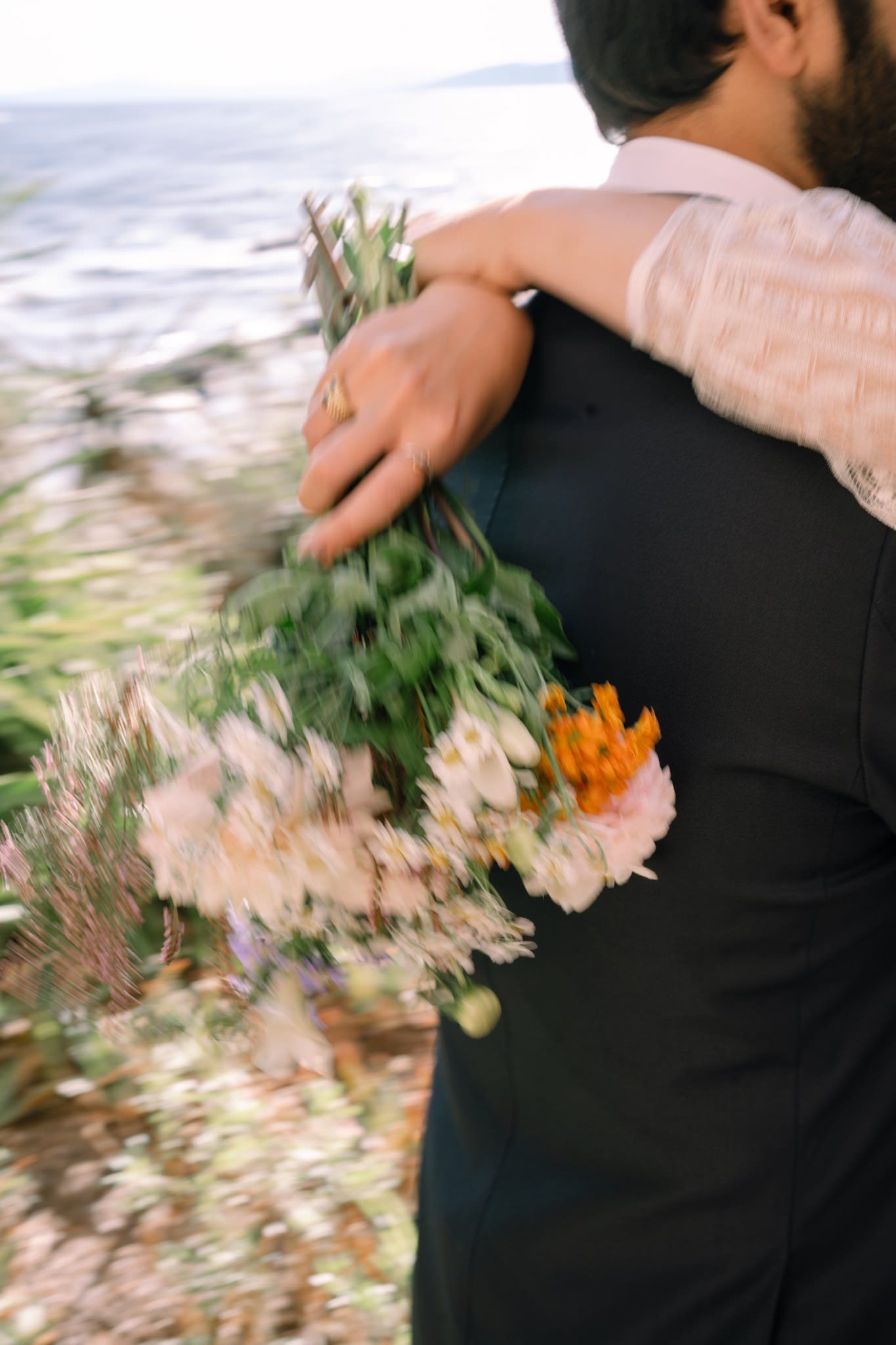 A wedding couple dances together while holding a colorful bouquet of flowers in motion.