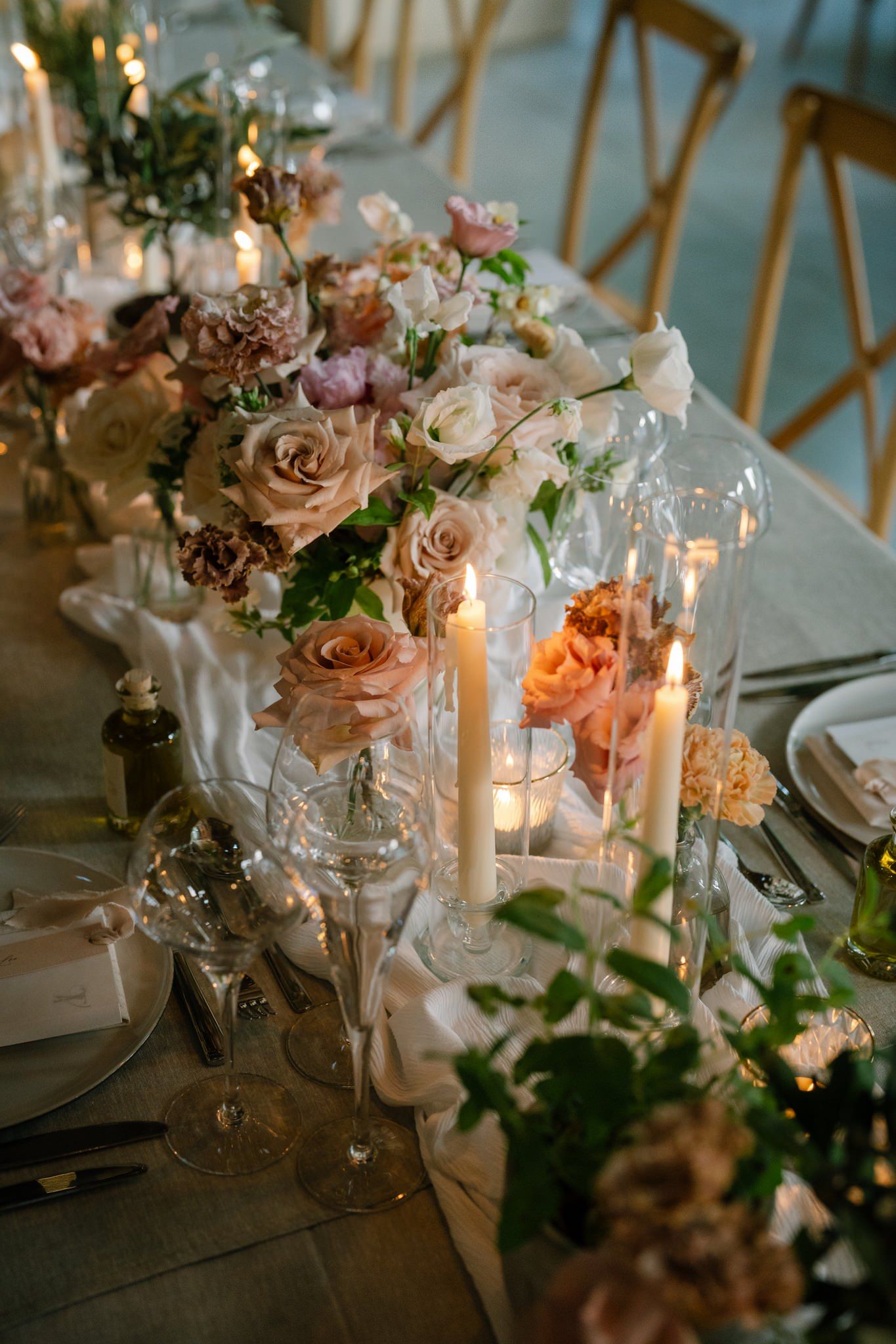 Elegant wedding table setting with pink flowers, candles and delicate glassware.
