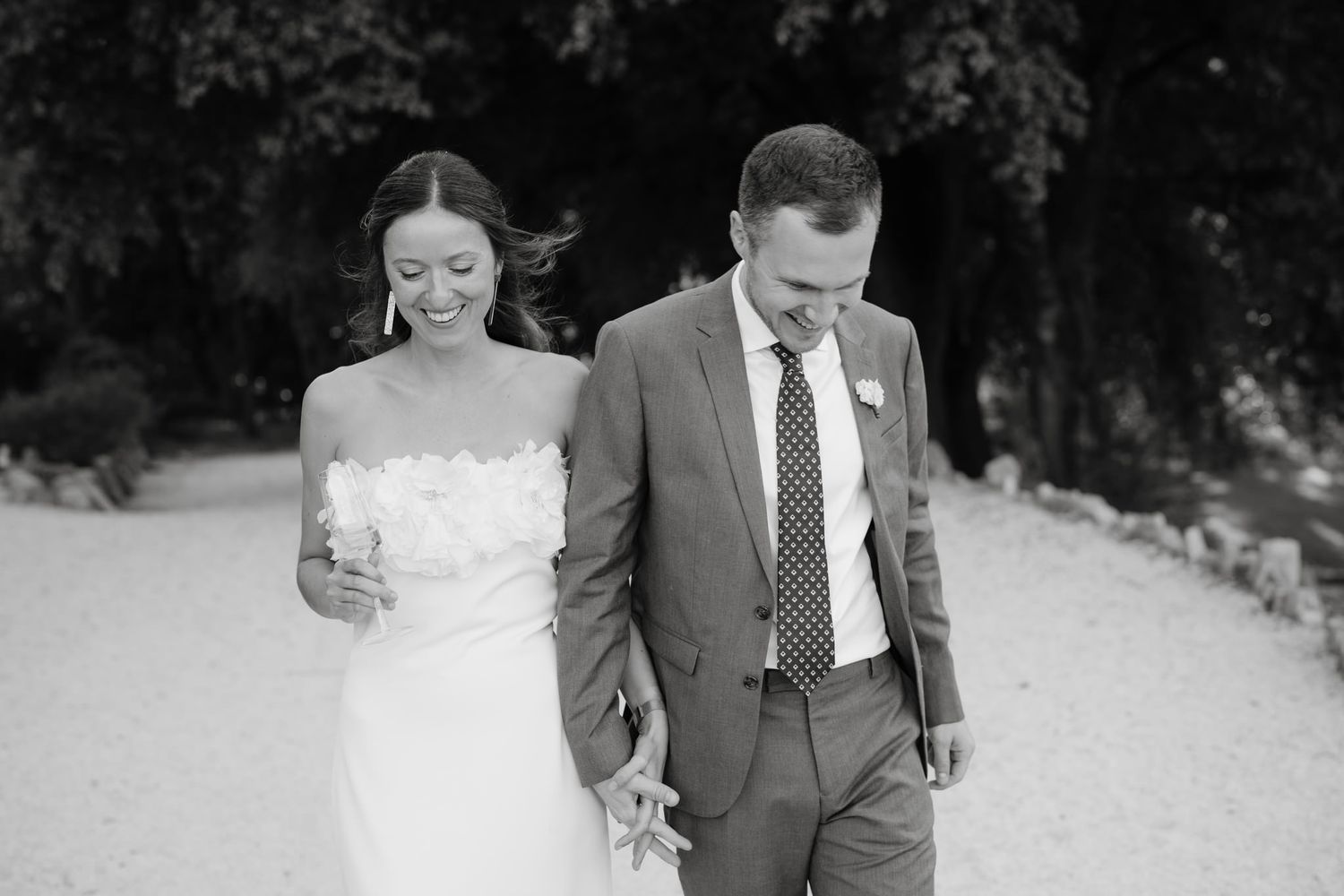 A couple walking together outdoors in formal wedding attire.