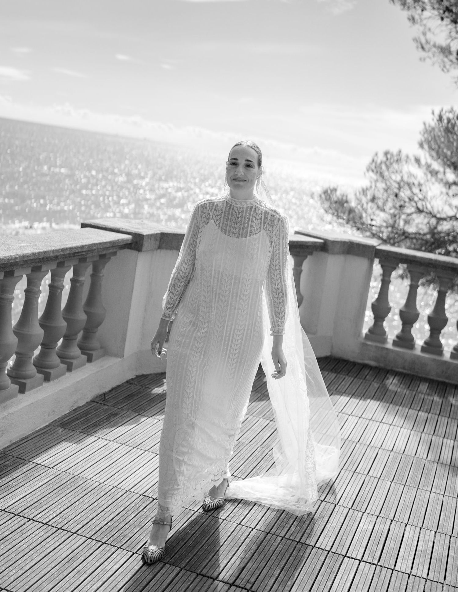 Elegant white wedding dress photographed on a terrace with stone balustrades and wooden decking.