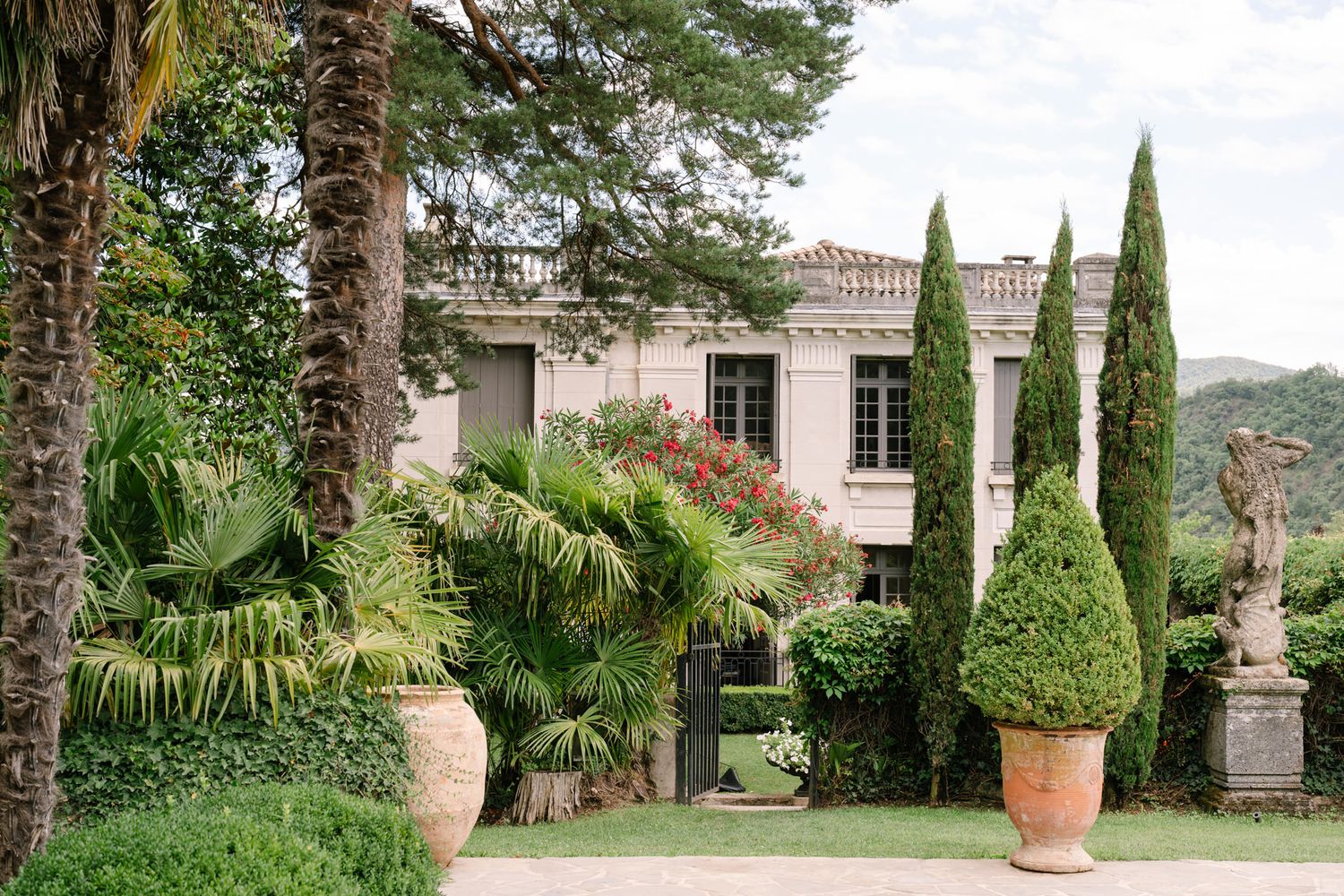 Tuscan villa exterior with cypress trees and stone architecture.