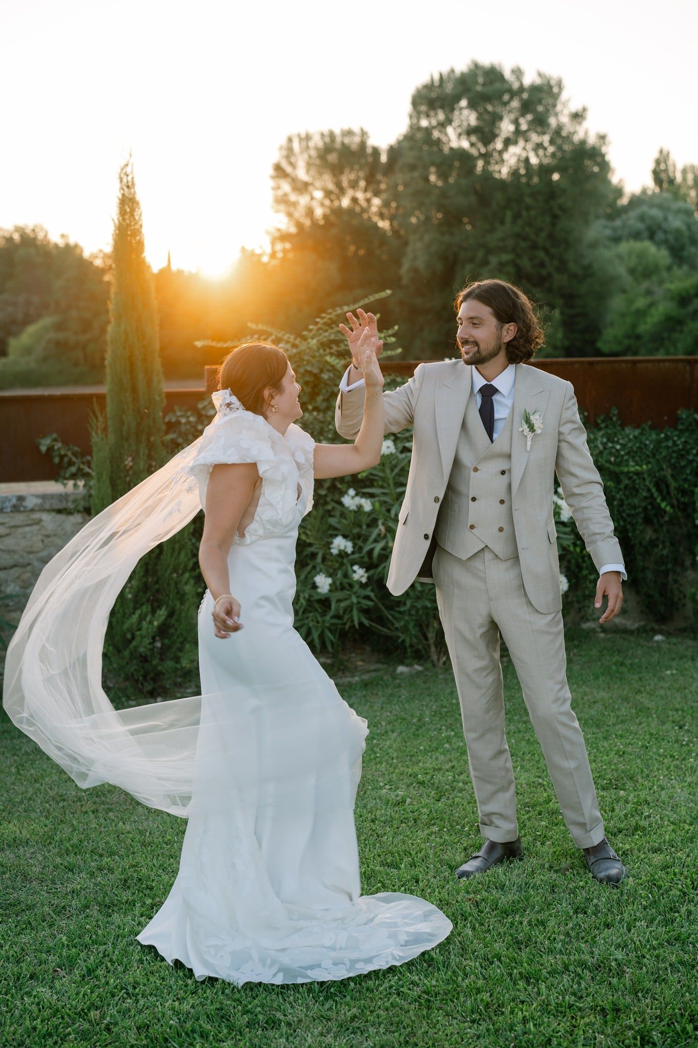 Couple dancing playfully on lawn during sunset wedding photoshoot.