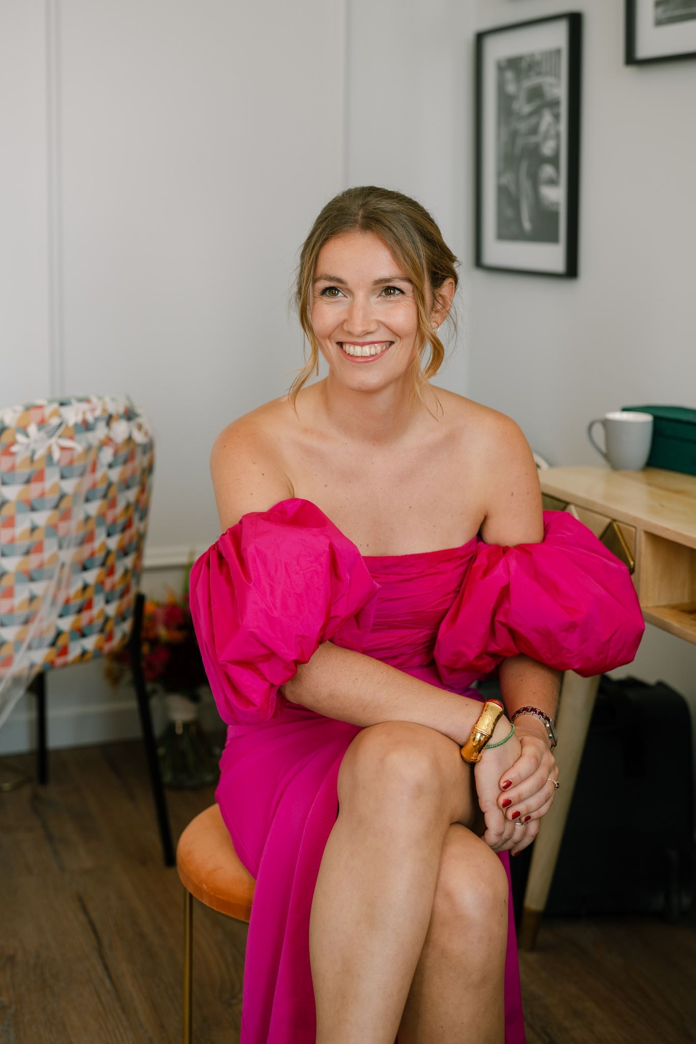Portrait series in a bright room wearing a vibrant pink off-shoulder dress.