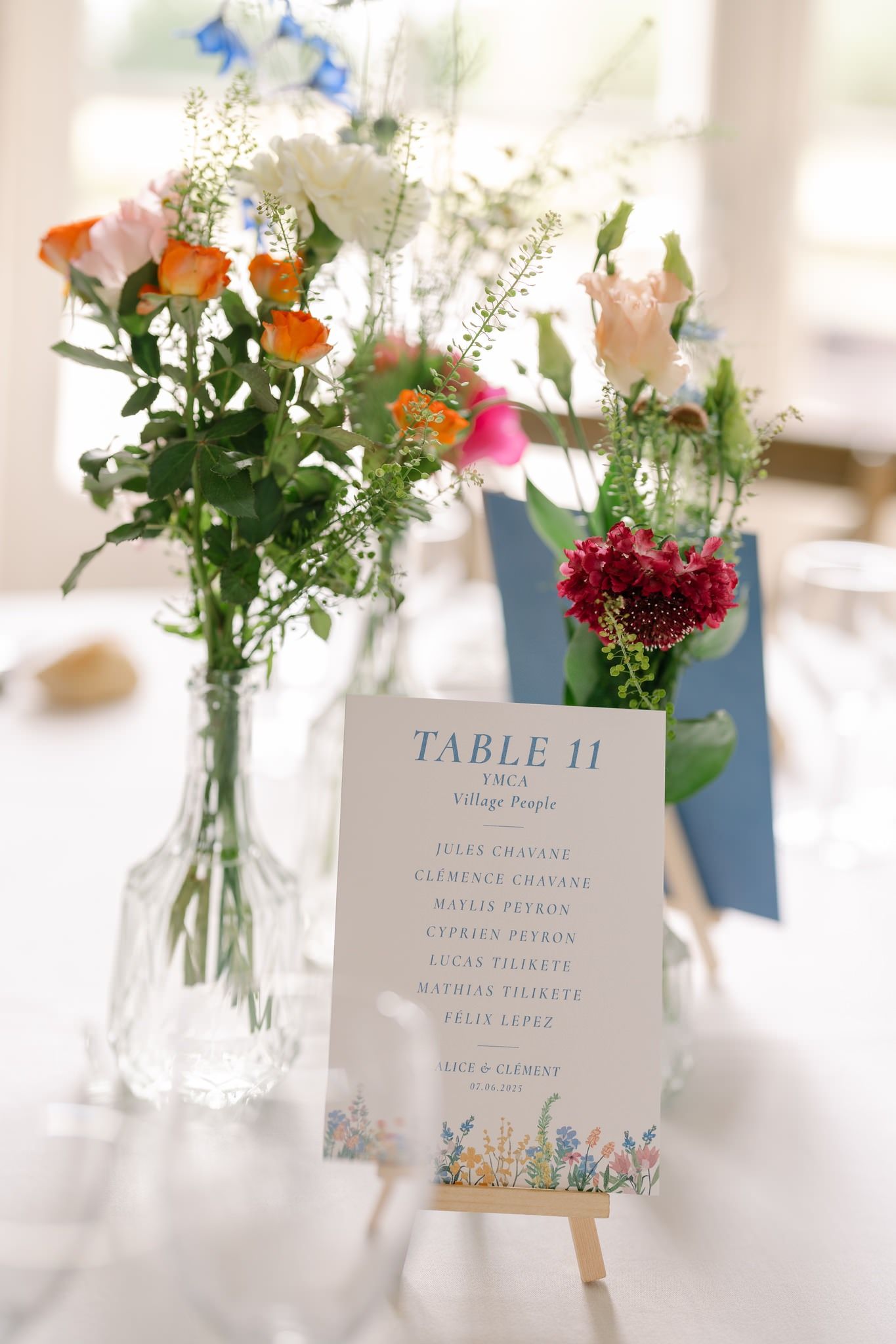 Wedding table numbers with delicate floral arrangements in small glass vases.