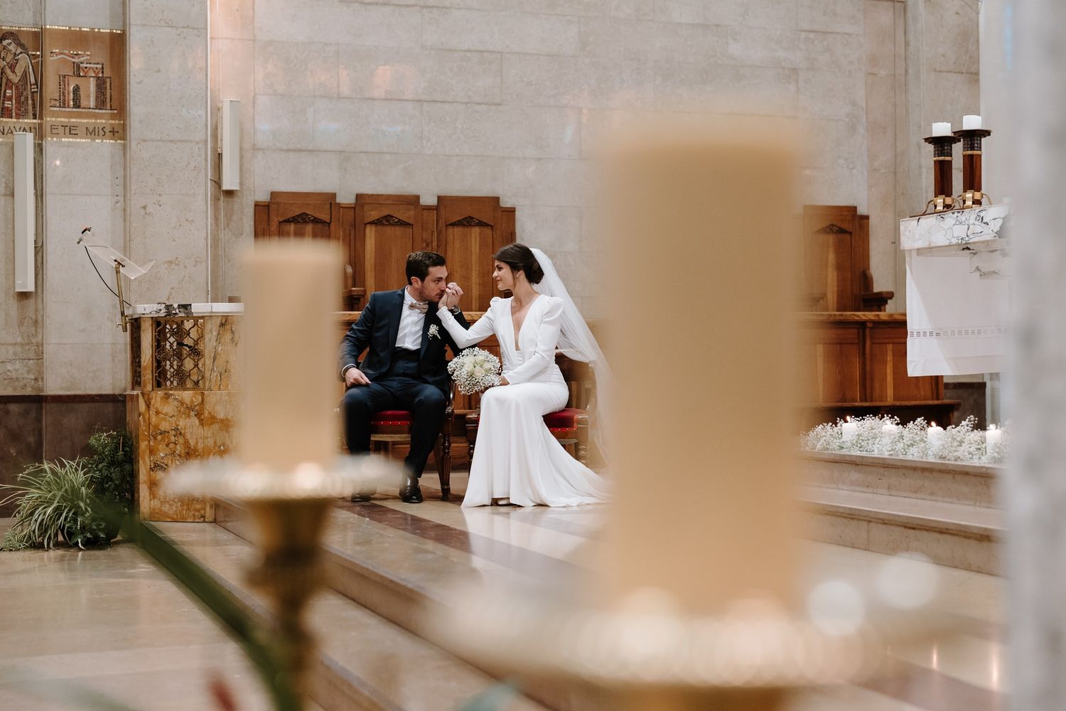 Artistic wedding photograph through blurred foreground elements in church setting.