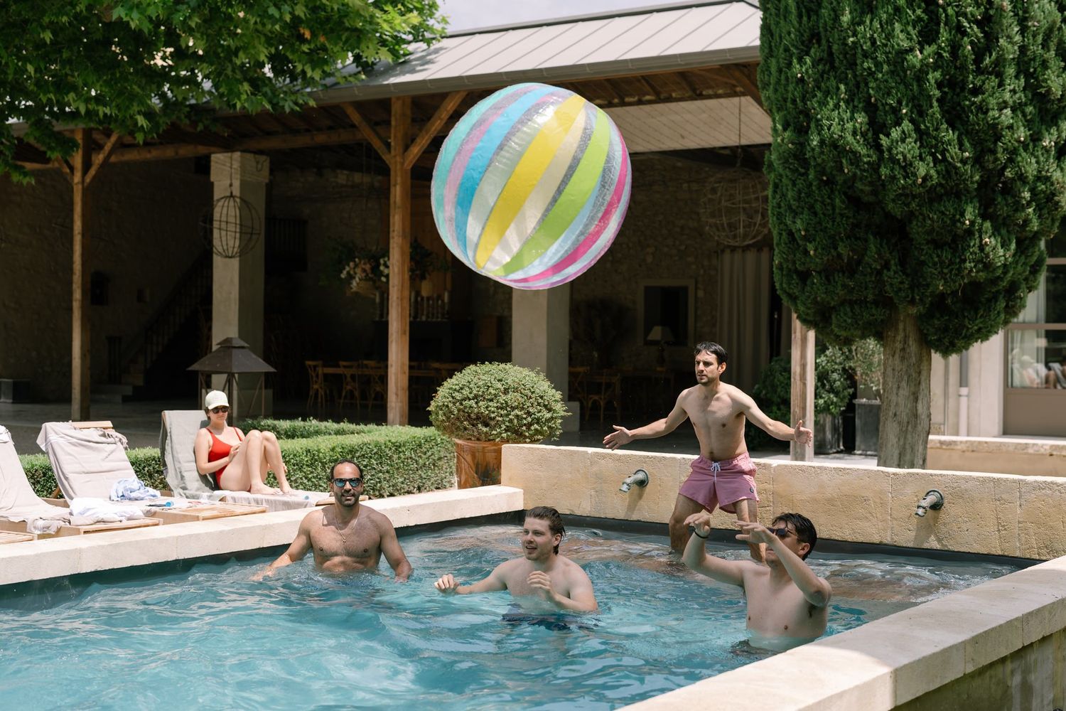 Group of people enjoying a pool party with colorful beach balls.