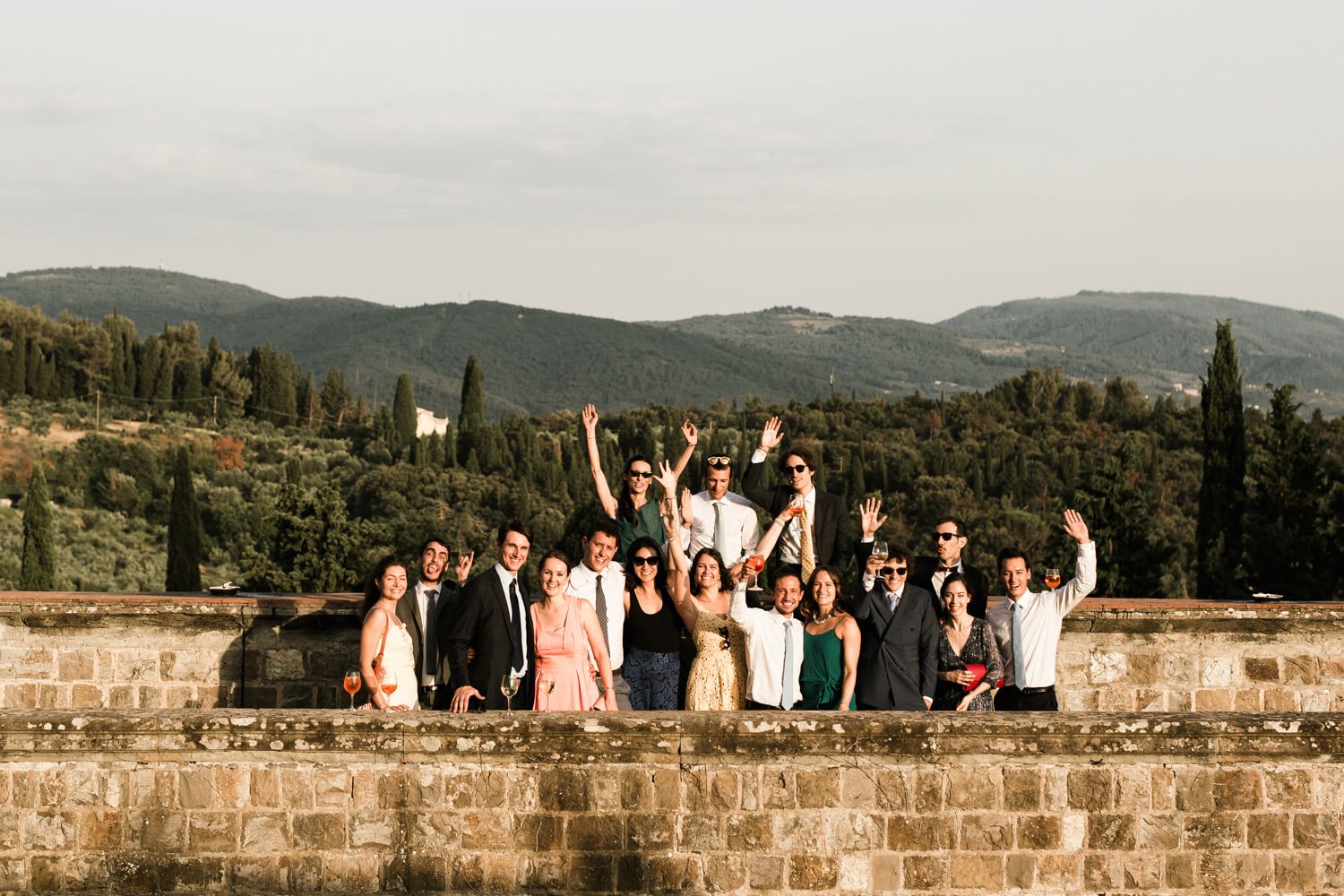 Wedding party posing on ancient stone walls with scenic mountain views in the background.