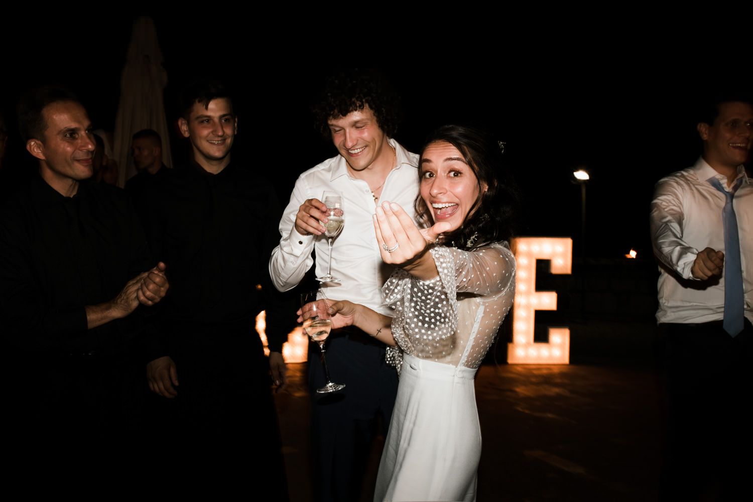 Wedding party dancing and celebrating during an evening reception with candlelight.