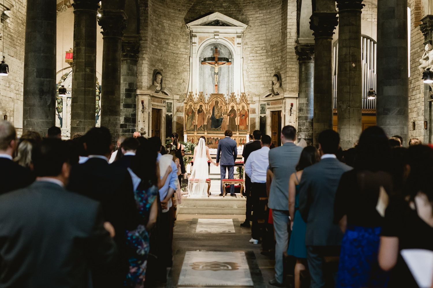 Wide view of church sanctuary during wedding ceremony with guests and altar in view.