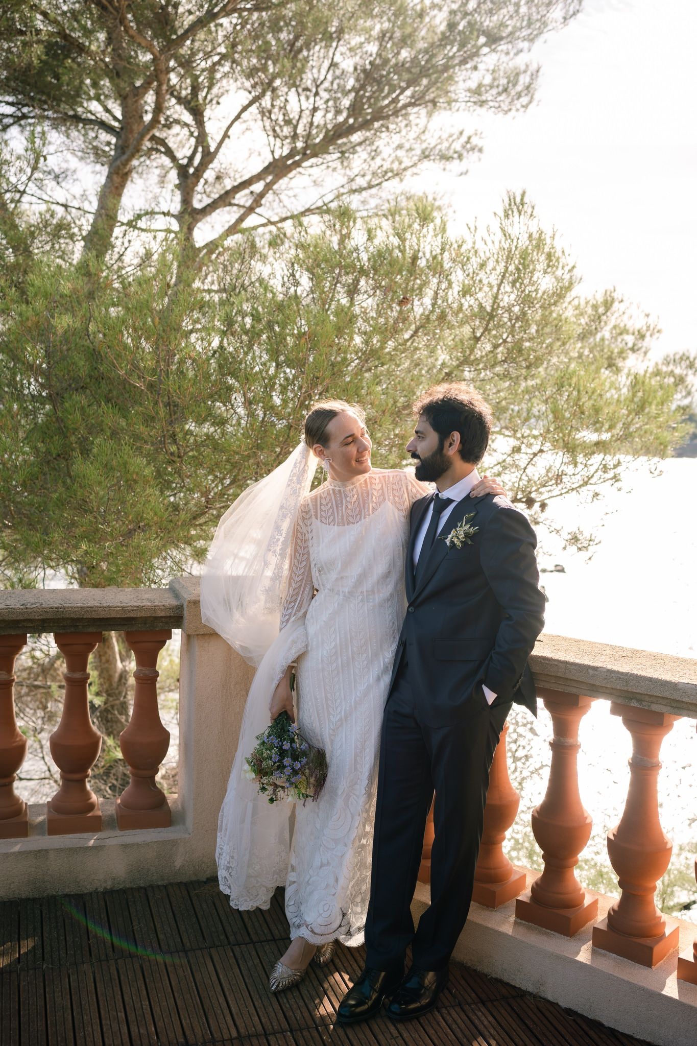 A romantic wedding photoshoot on a Mediterranean terrace with stone balusters and pine trees.
