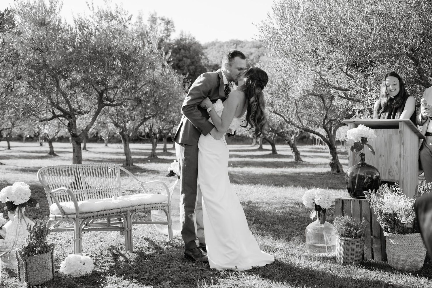 Black and white photo of wedding ceremony setup in an olive grove with wooden benches.