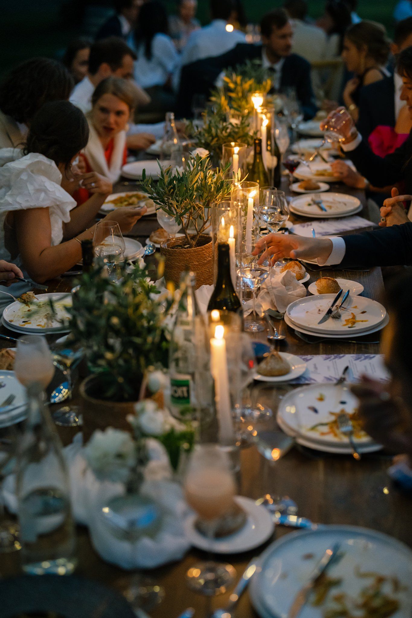 Elegant table settings with candlelight and greenery at a wedding reception dinner.