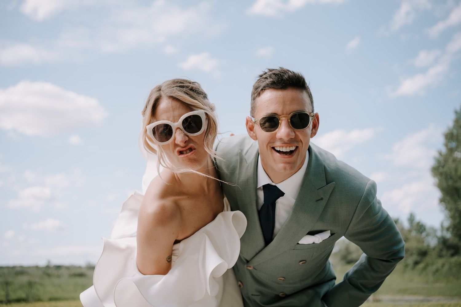 Wedding couple sharing joyful moments outdoors on a sunny summer day.