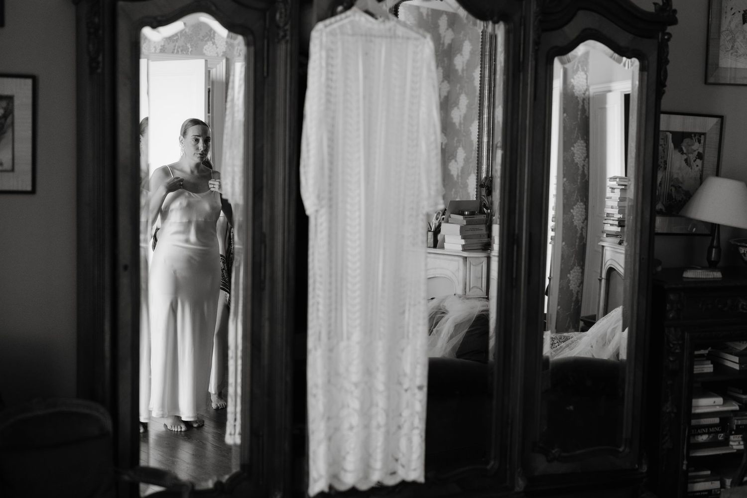 Elegant vintage triple mirror armoire with lace curtain reflection in black and white.