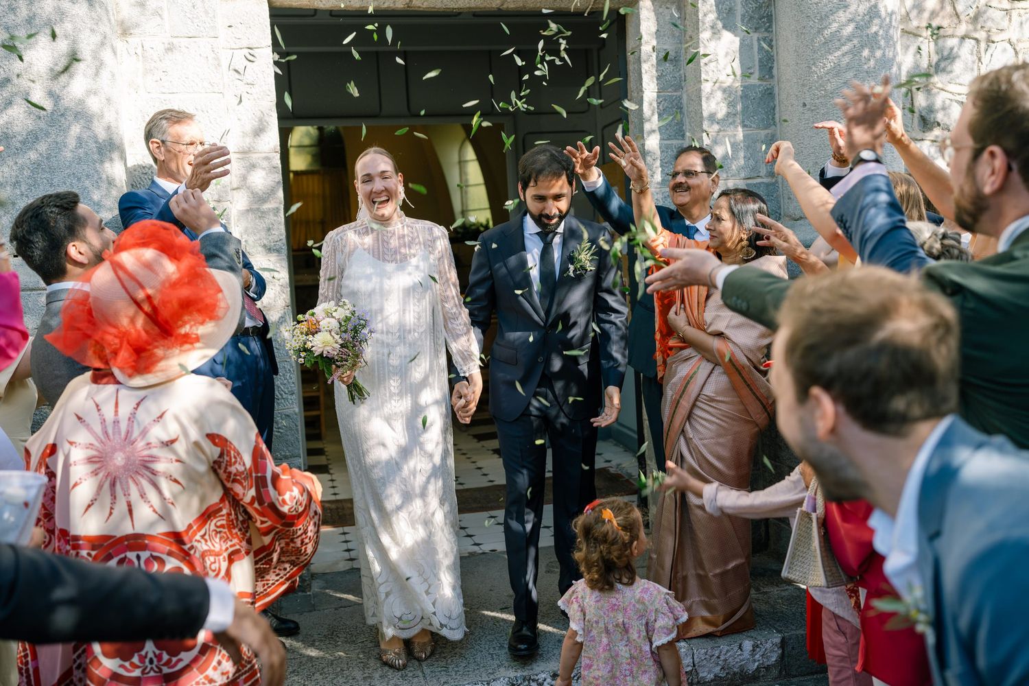 Wedding guests throw confetti outside church during joyful celebration.