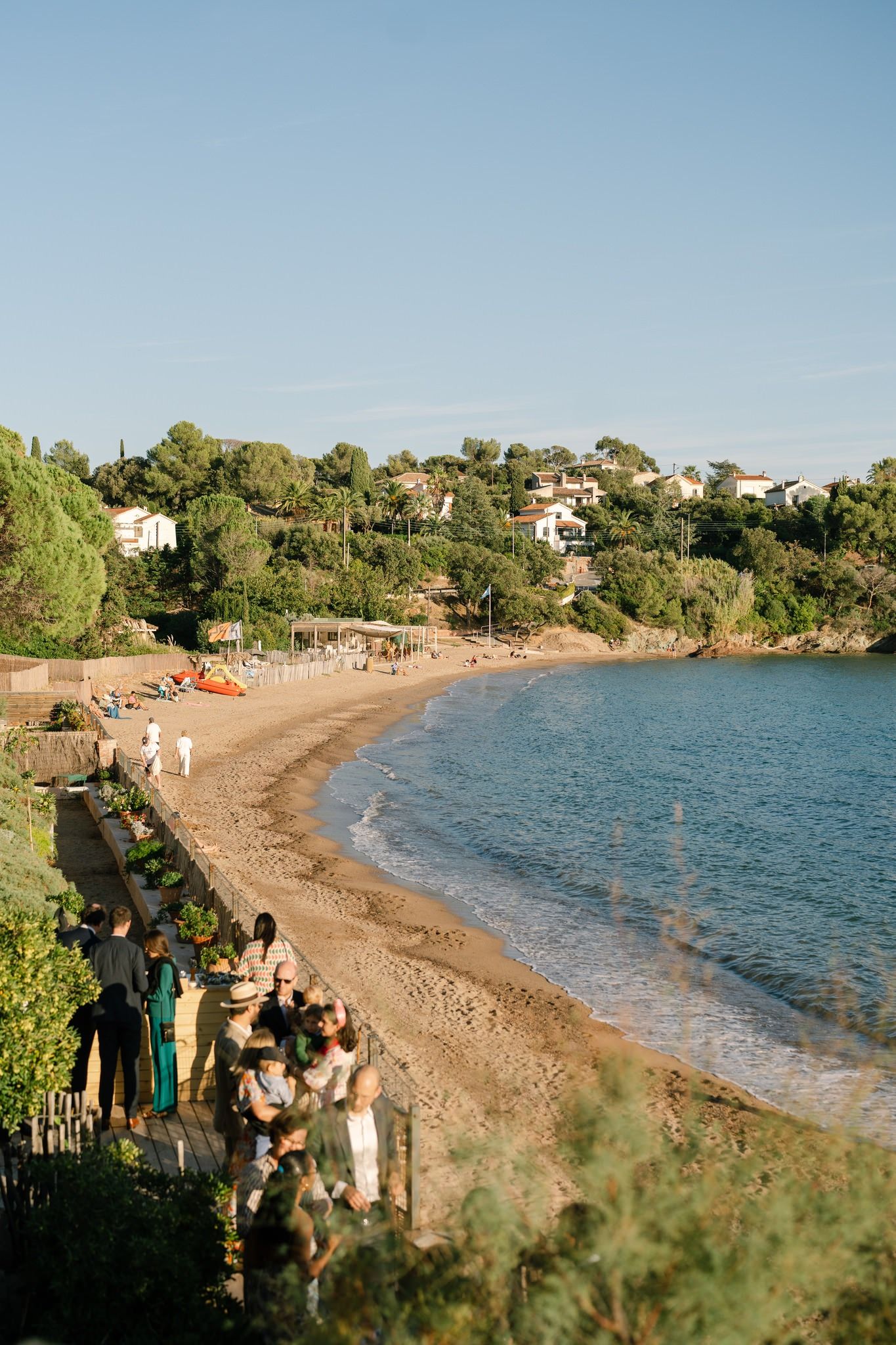 Curved beach cove with blue water and lush vegetation along the coastline.