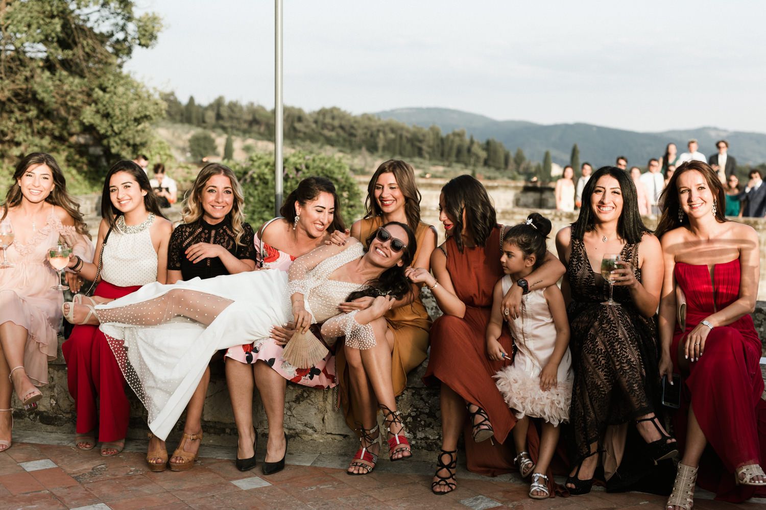 Wedding guests relaxing and socializing on stone steps during an outdoor celebration.