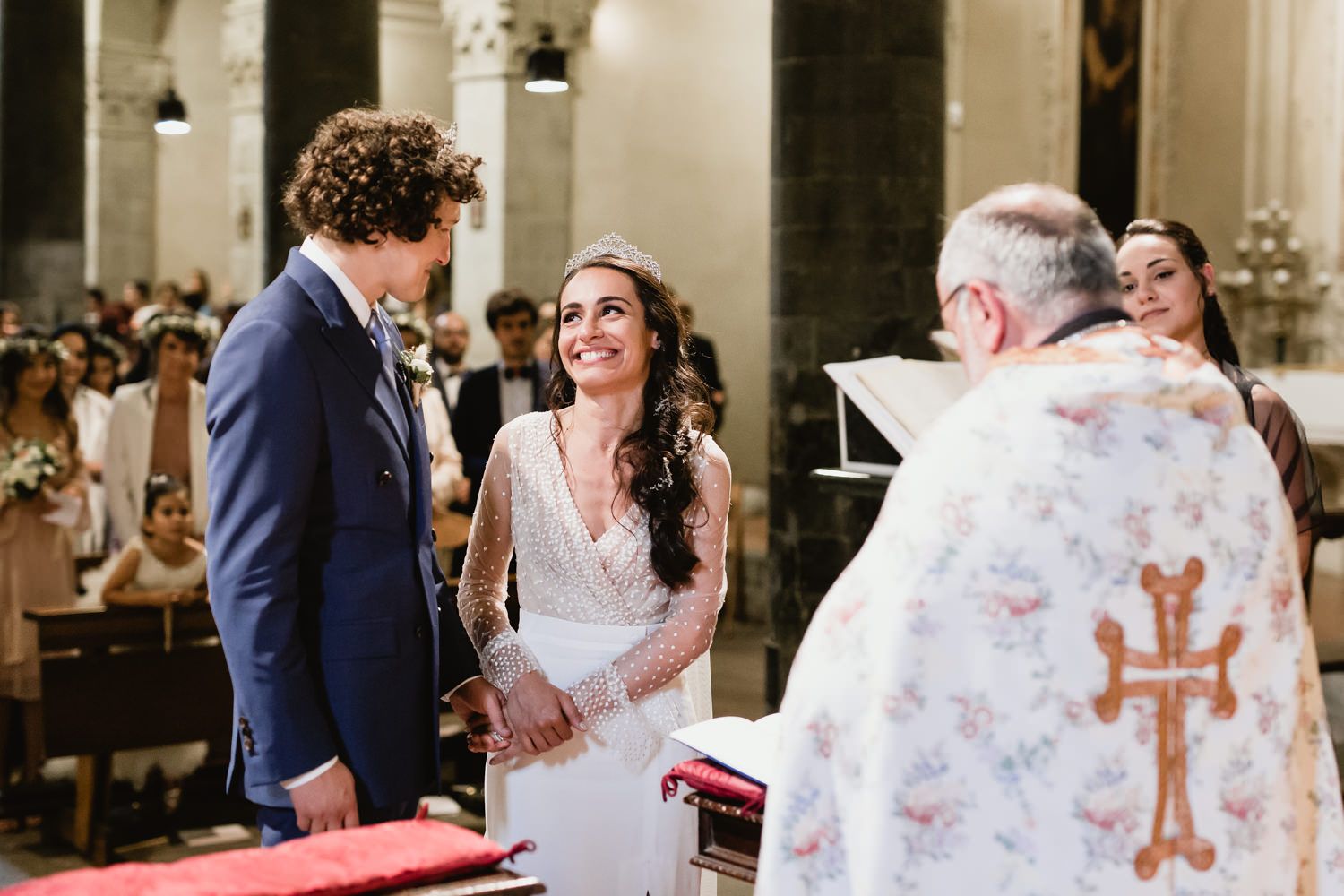 Wedding ceremony in progress showing decorative church interior with floral accents.