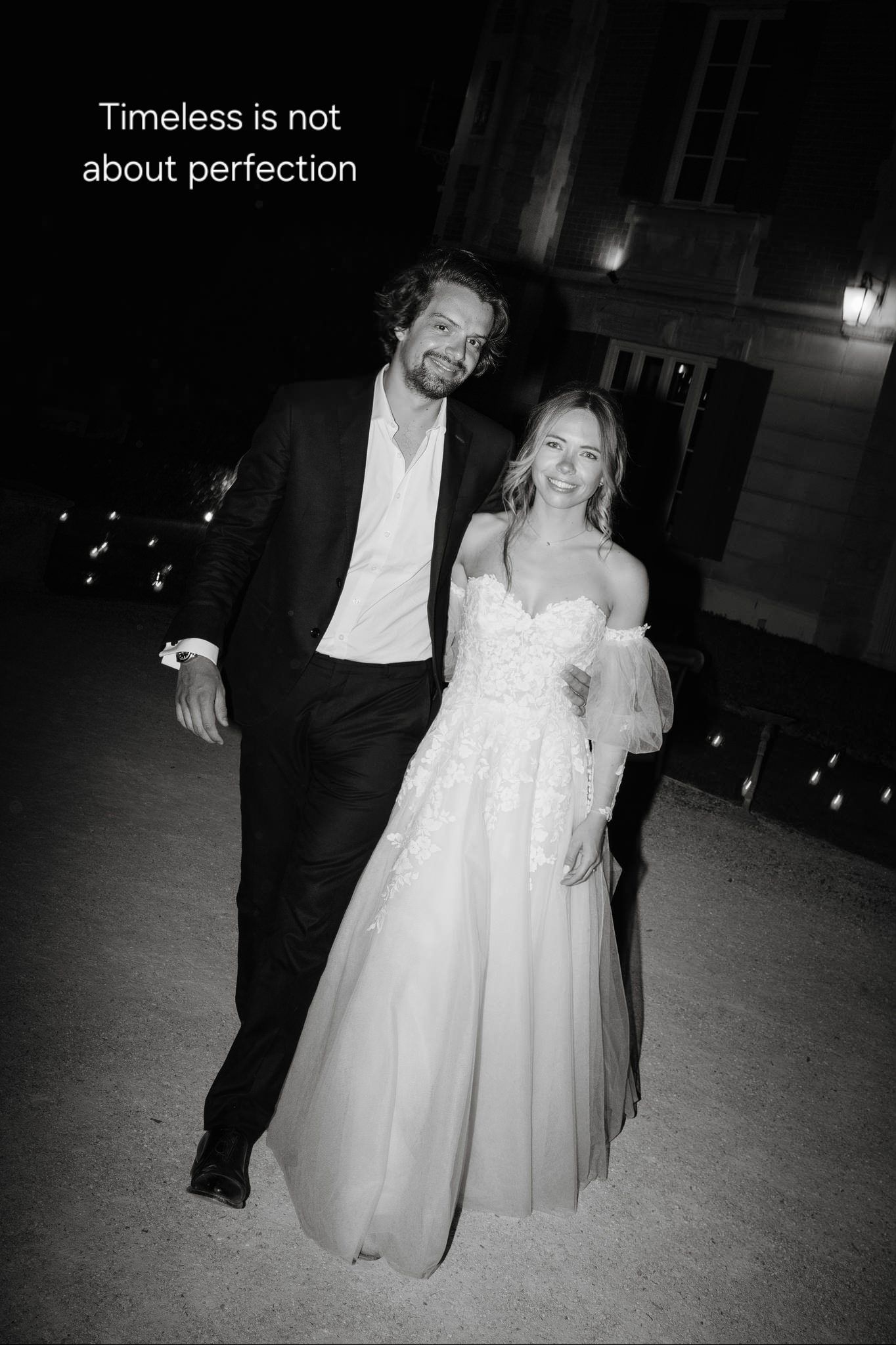 A nighttime black and white wedding photo of a couple walking.