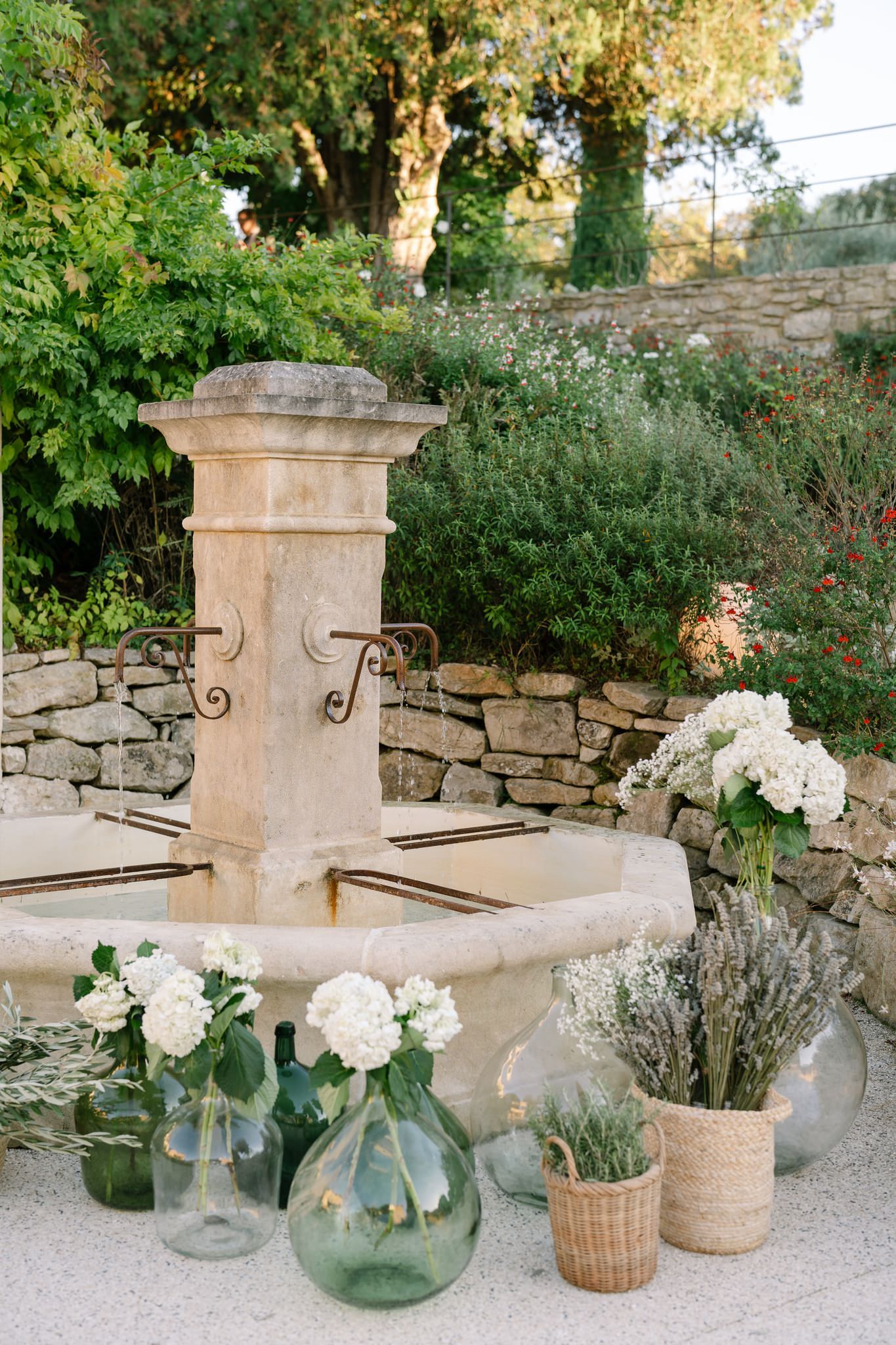Stone wall with decorative white hydrangeas in glass vases and woven baskets.