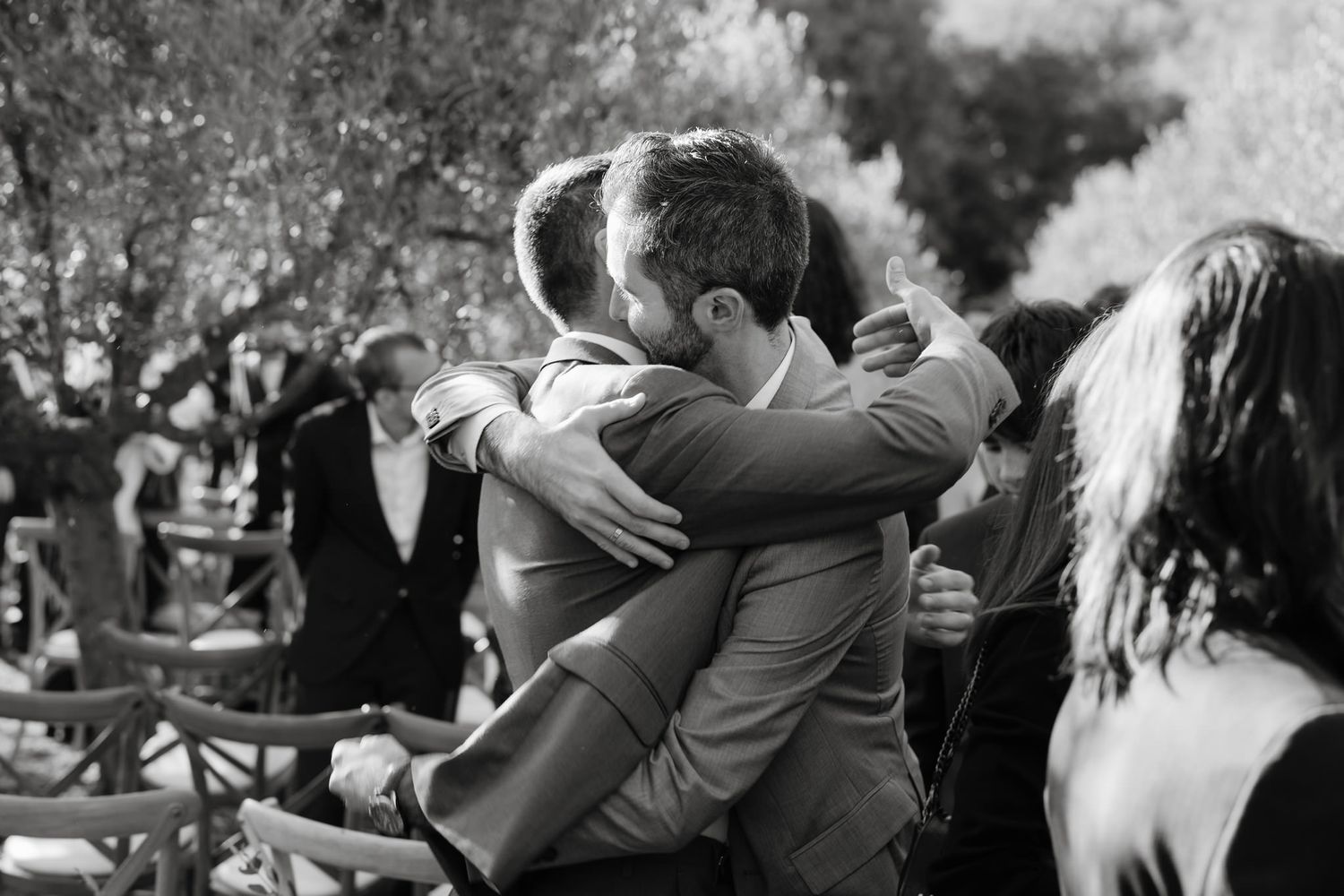 Black and white photos capturing joyful wedding moments under olive trees.