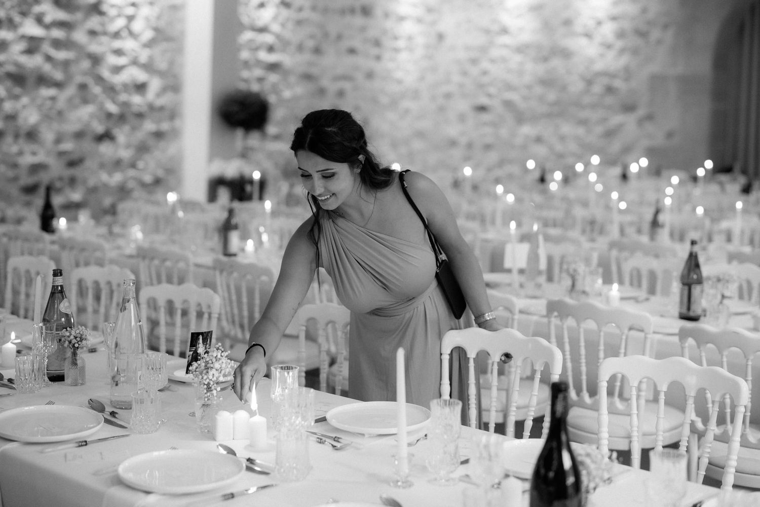 Elegant wedding reception setup with white chairs and candlelit tables in a rustic stone venue.