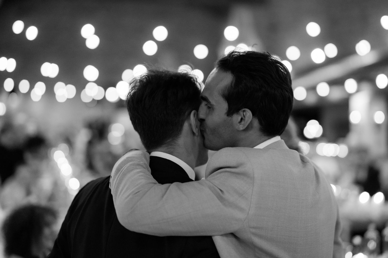 Dance floor filled with couples during an evening wedding reception under twinkling lights.