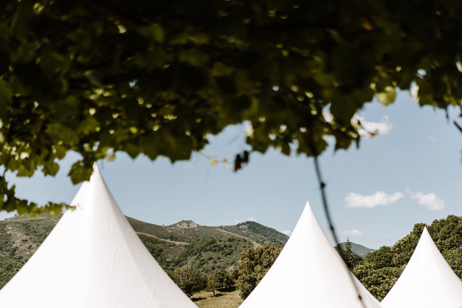 White event tents set up outdoors against a mountain landscape with blue skies.