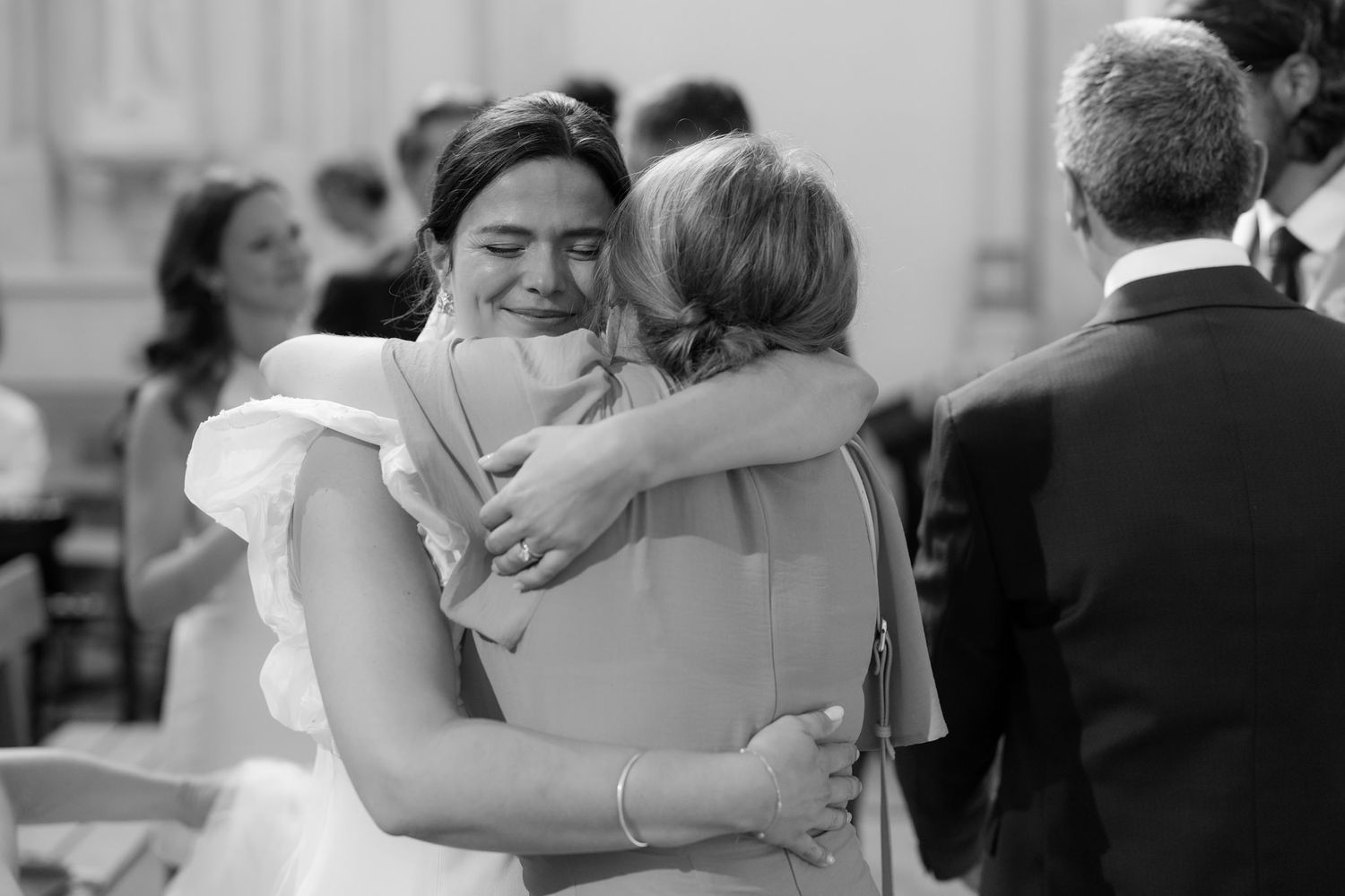 Emotional black and white photographs capturing heartfelt embraces during wedding celebrations.