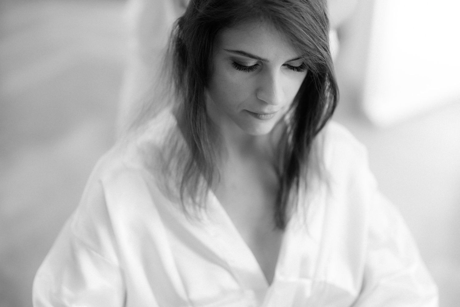 Soft black and white portrait of someone wearing a white robe in natural light.